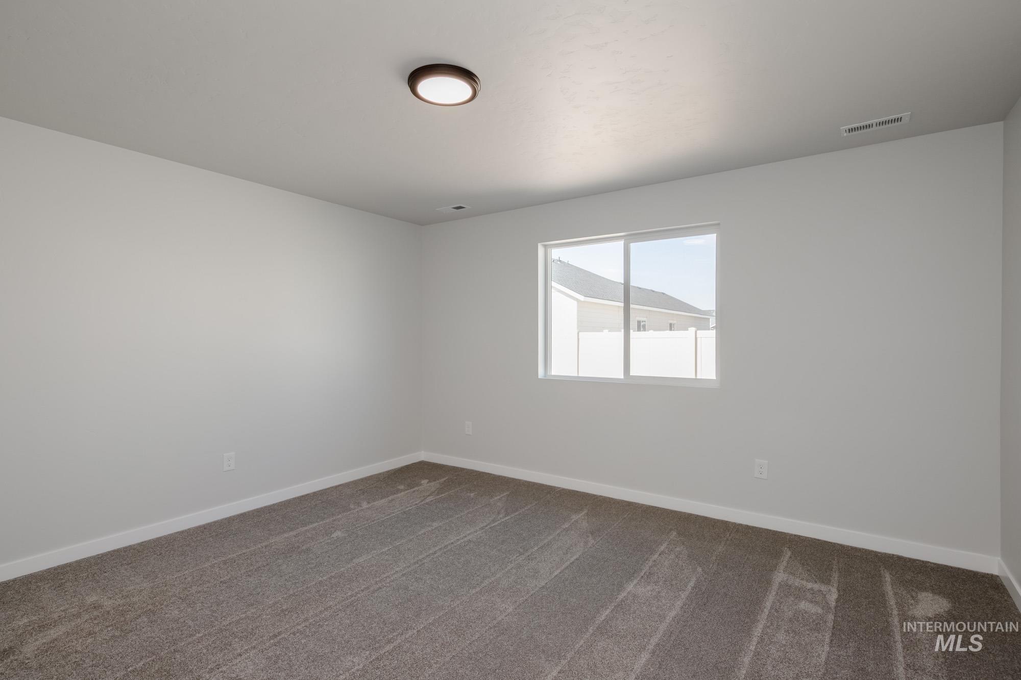 Unfurnished room with dark colored carpet and baseboards