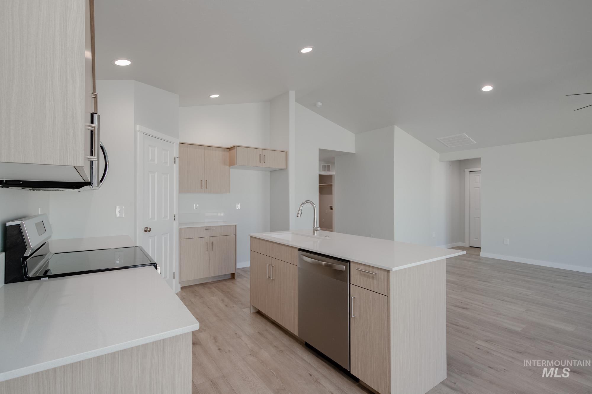 Kitchen featuring light brown cabinetry, recessed lighting, light wood-style floors, stainless steel appliances, and a kitchen island with sink