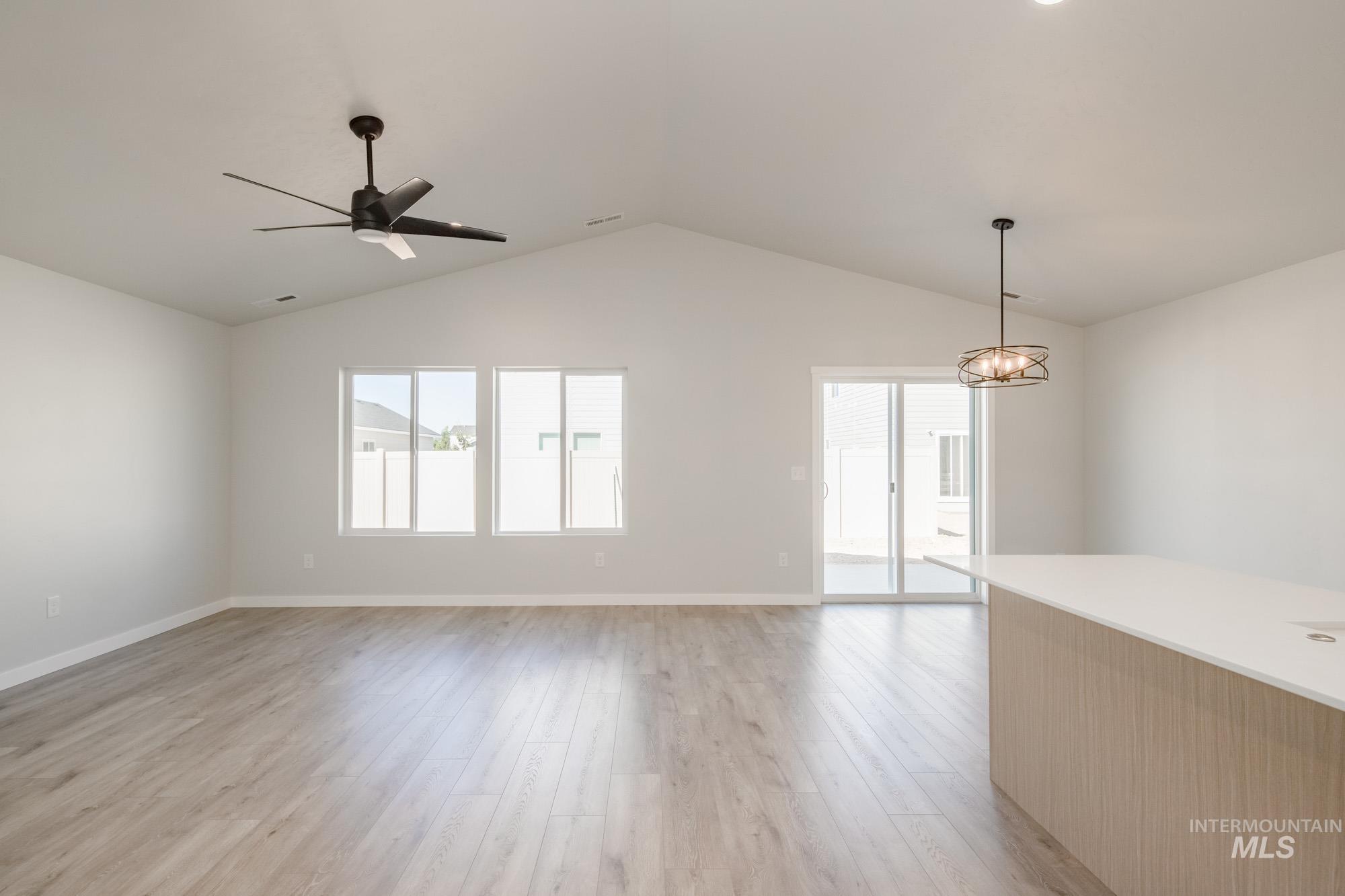 Spare room with light wood-style flooring, lofted ceiling, and a ceiling fan