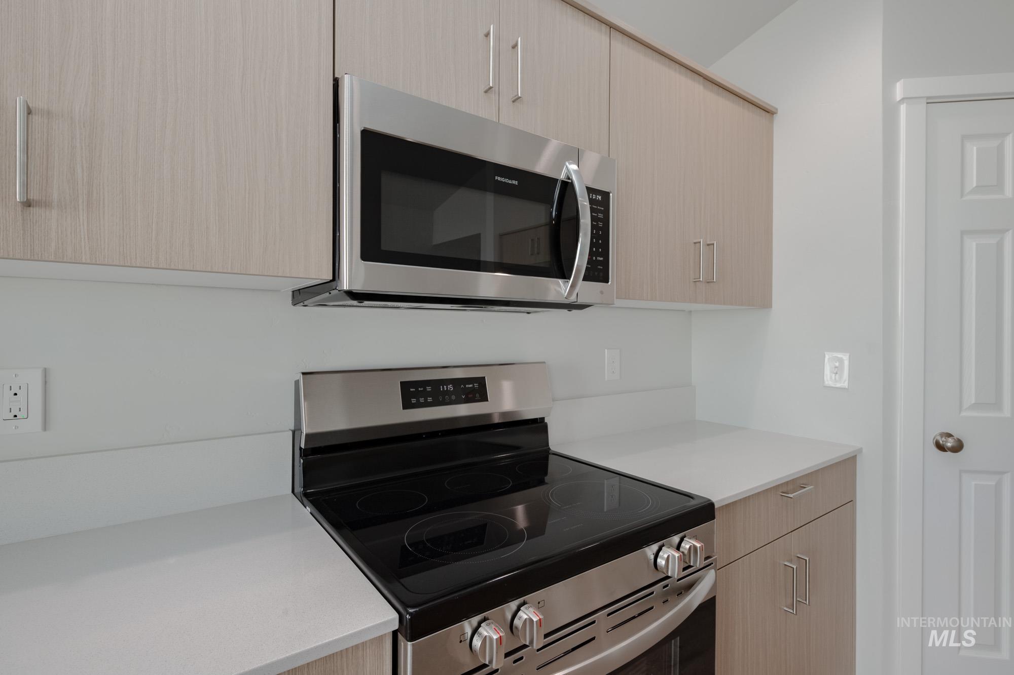 Kitchen featuring appliances with stainless steel finishes, modern cabinets, light brown cabinetry, and light stone countertops