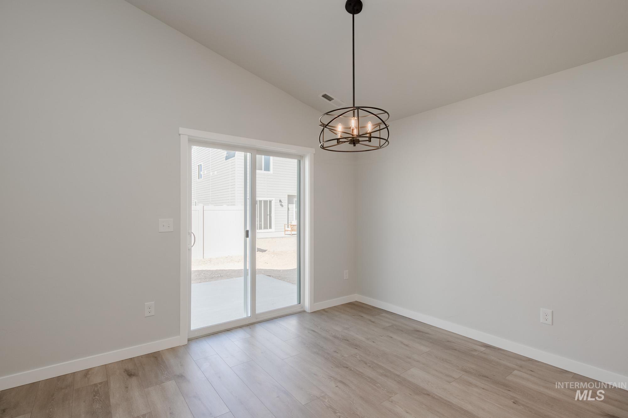 Spare room featuring lofted ceiling, light wood-style floors, and a chandelier