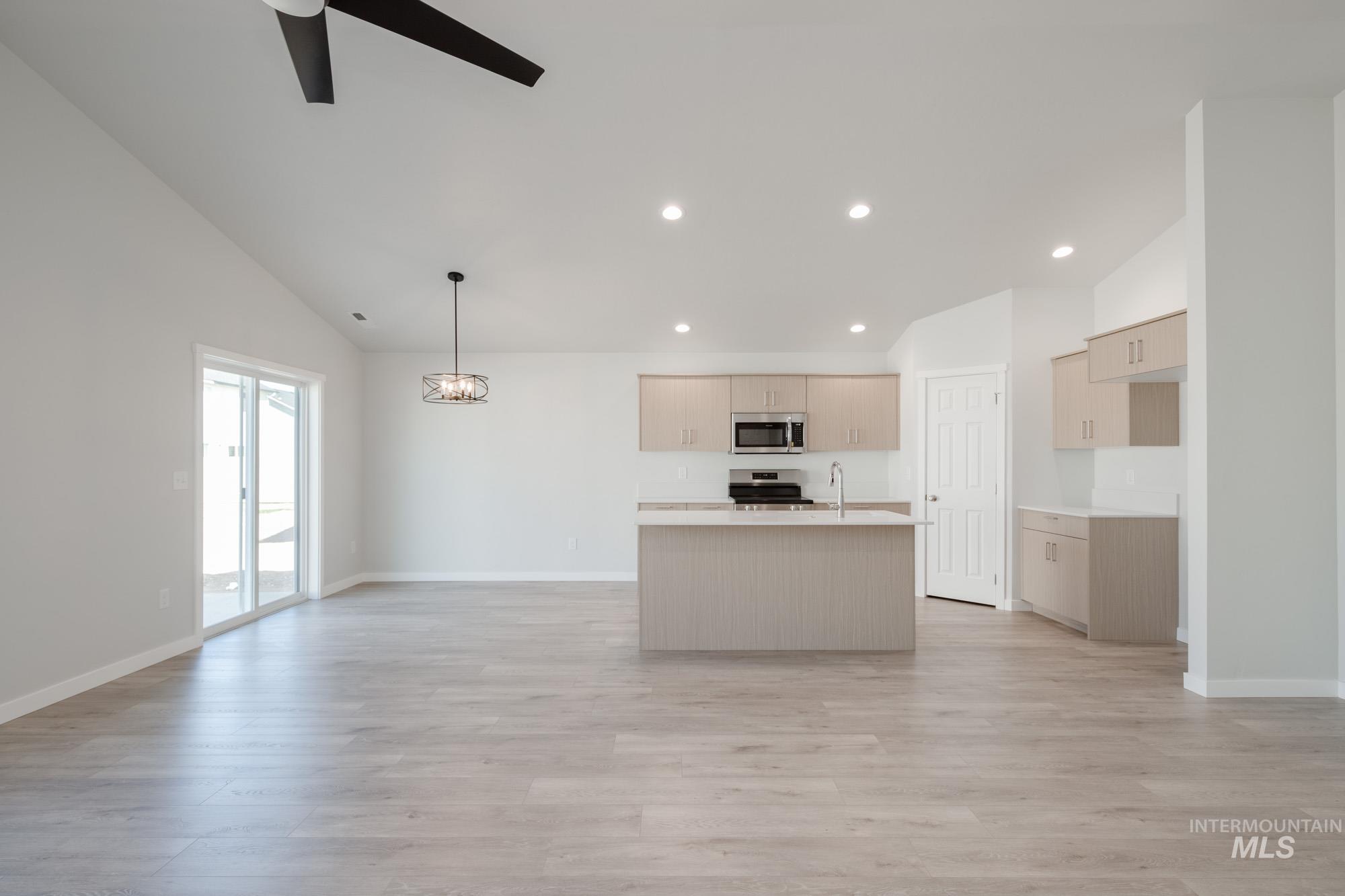 Kitchen featuring open floor plan, an island with sink, light countertops, light wood finished floors, and recessed lighting