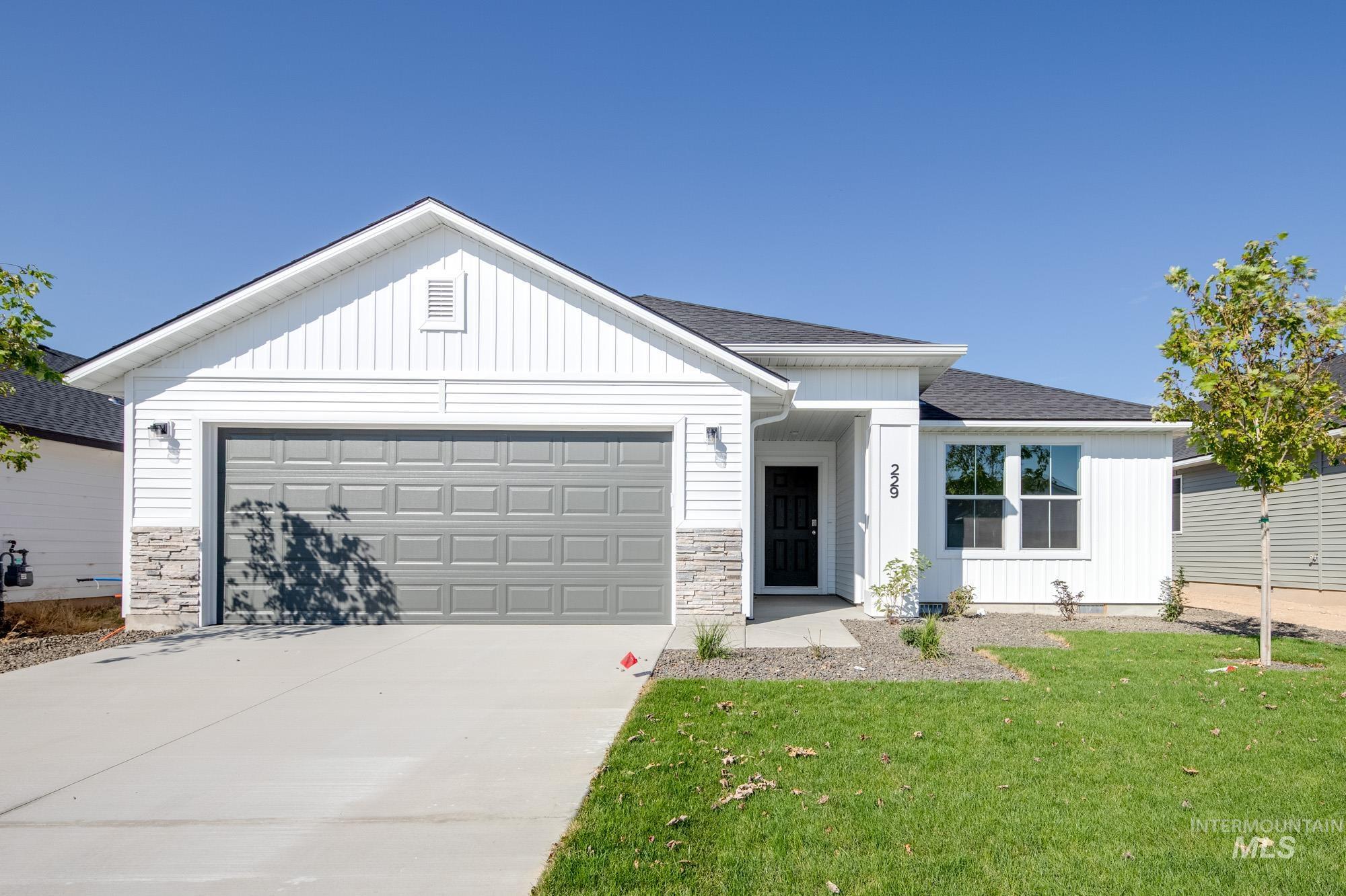 View of front of house with stone siding, driveway, board and batten siding, and roof with shingles