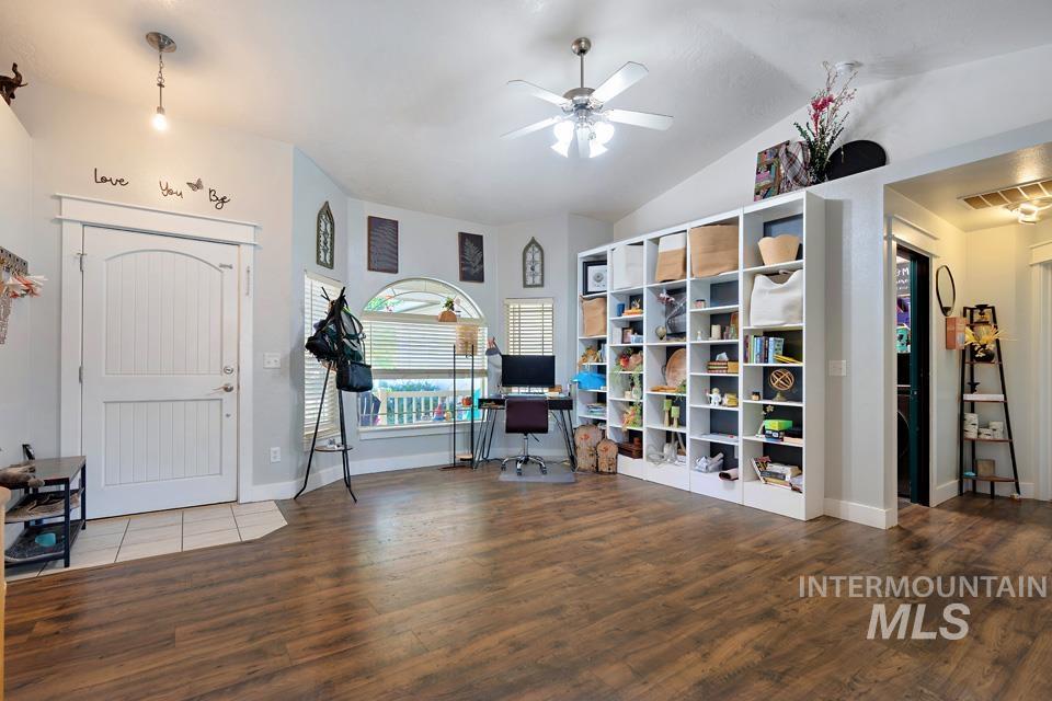 Living area with a desk, wood finished floors, a ceiling fan, and vaulted ceiling