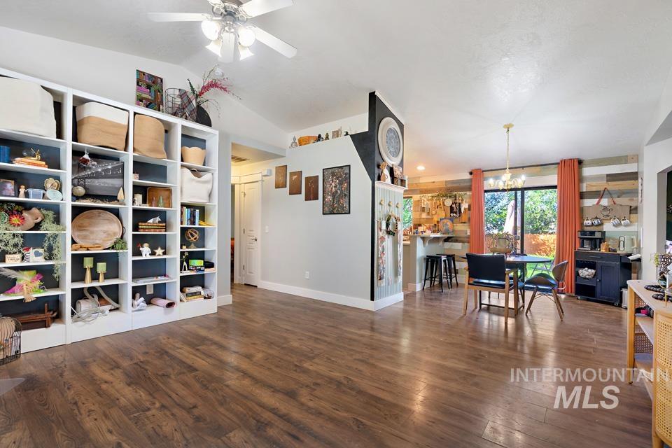 Rec room featuring dark wood finished floors, lofted ceiling, a chandelier, and ceiling fan