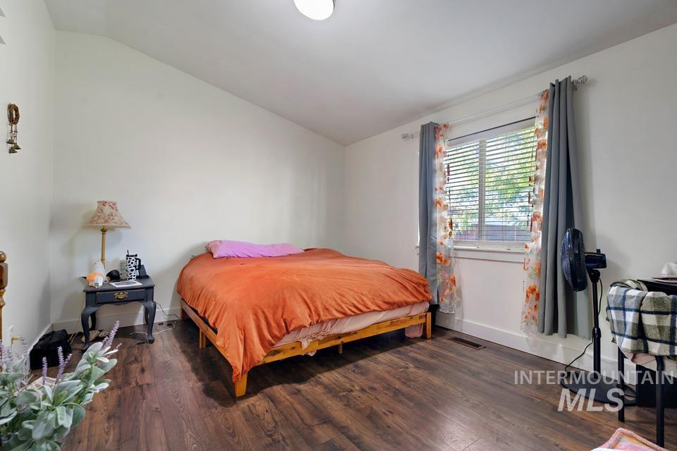 Bedroom with vaulted ceiling and dark wood-style flooring