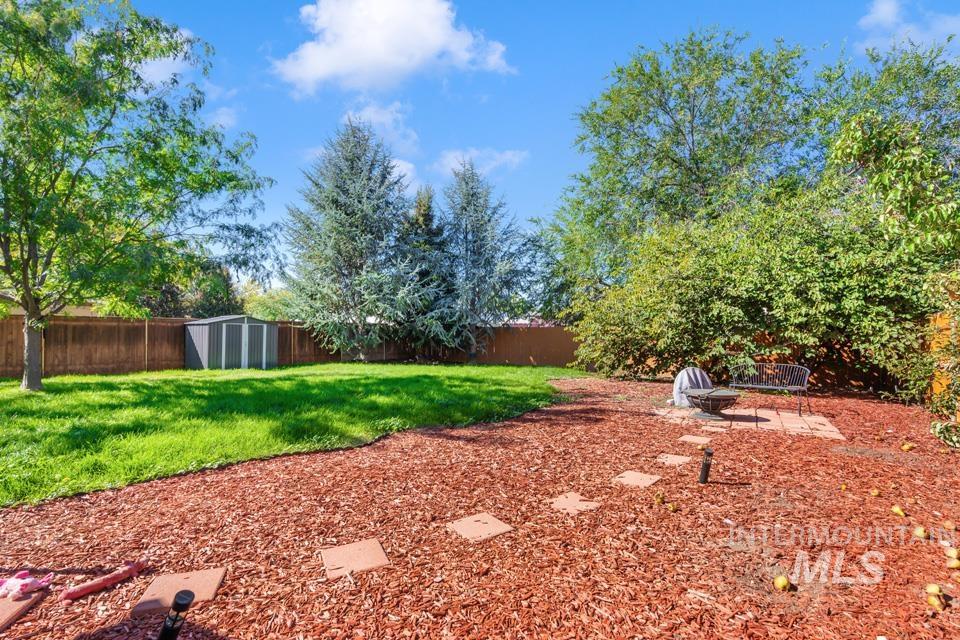 Fenced backyard featuring an outdoor fire pit, a shed, and a patio