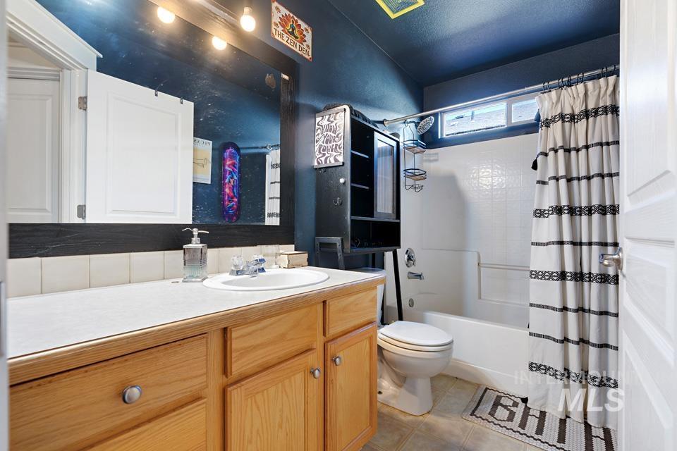 Bathroom with vanity, shower / bath combo, and light tile patterned flooring
