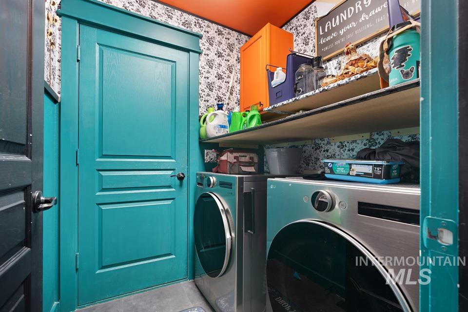 Washroom with tile patterned flooring, separate washer and dryer, and wallpapered walls