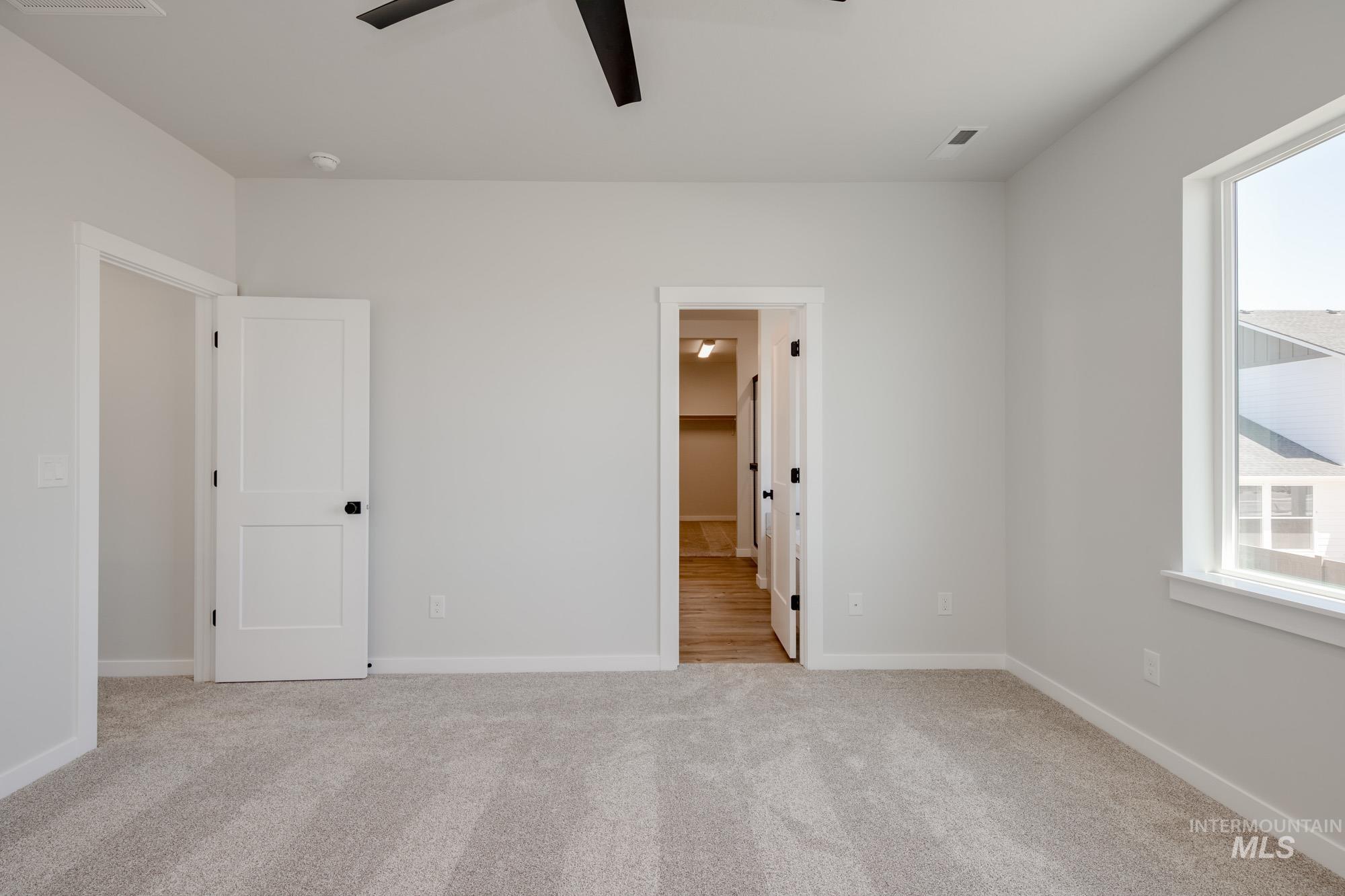 Unfurnished bedroom featuring carpet, ensuite bathroom, and ceiling fan