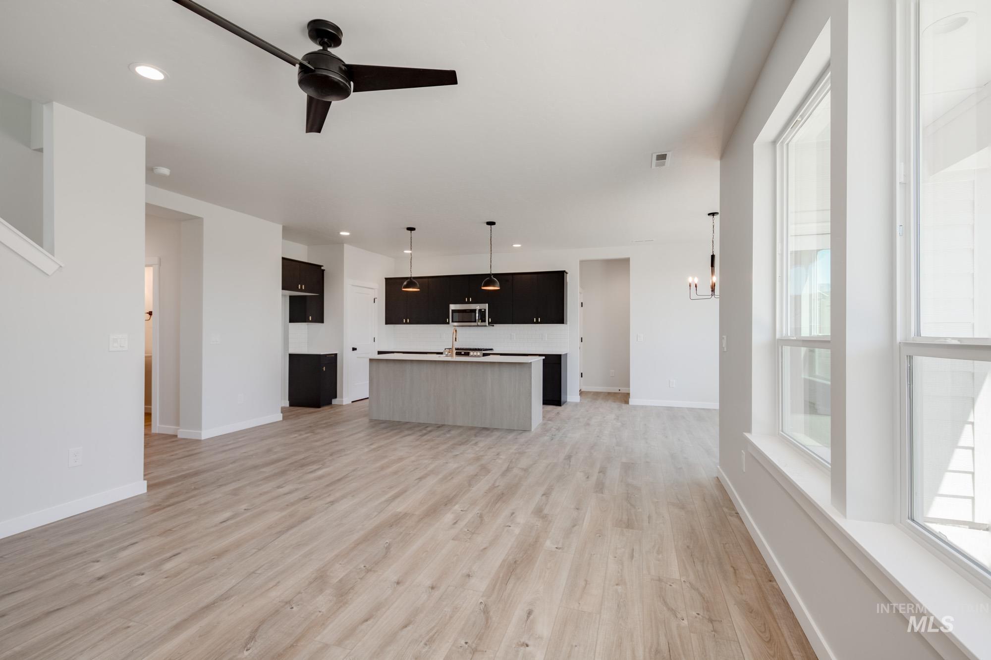 Unfurnished living room featuring a ceiling fan, light wood-type flooring, recessed lighting, and a chandelier