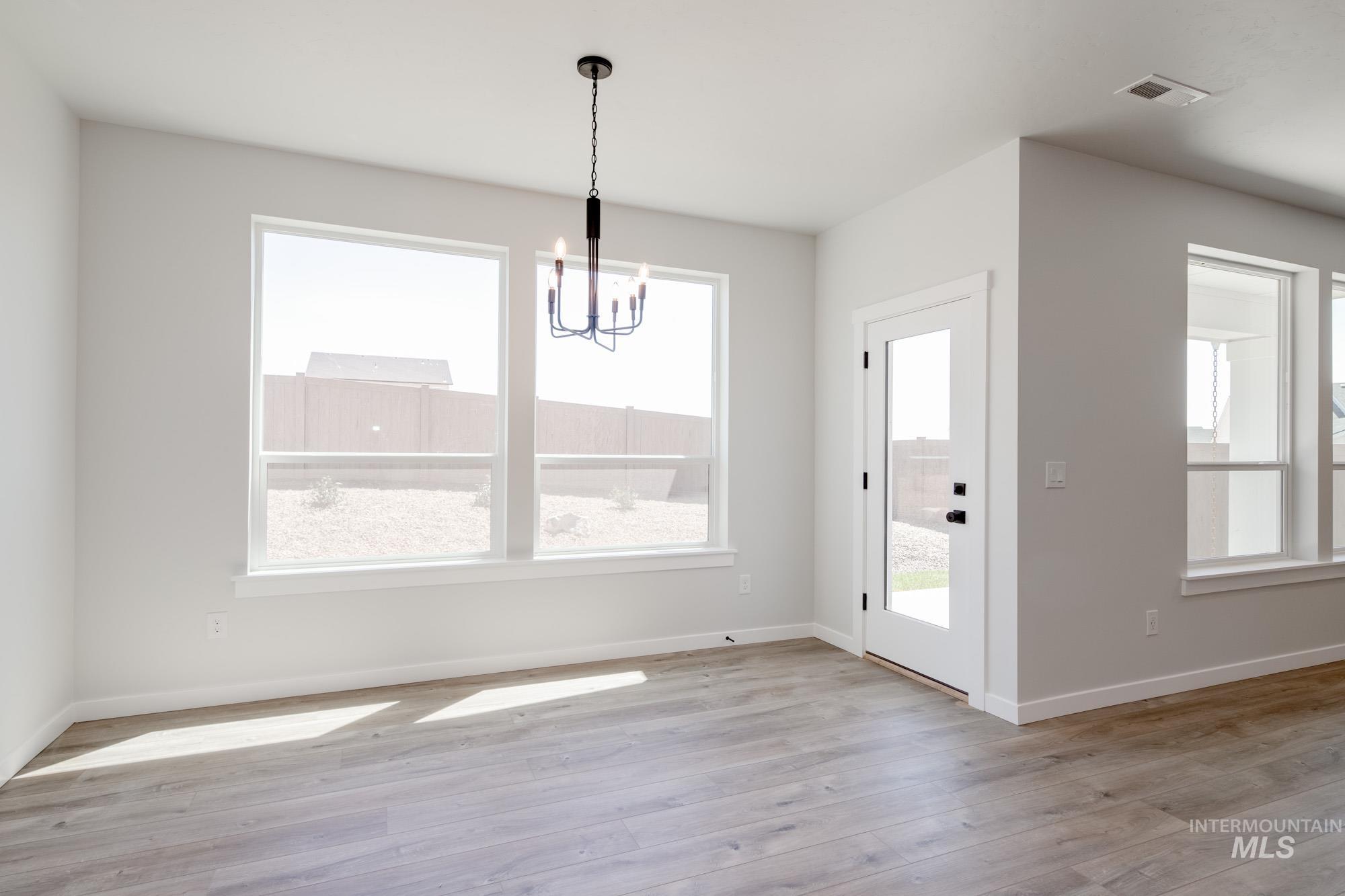 Unfurnished dining area with a chandelier and light wood finished floors