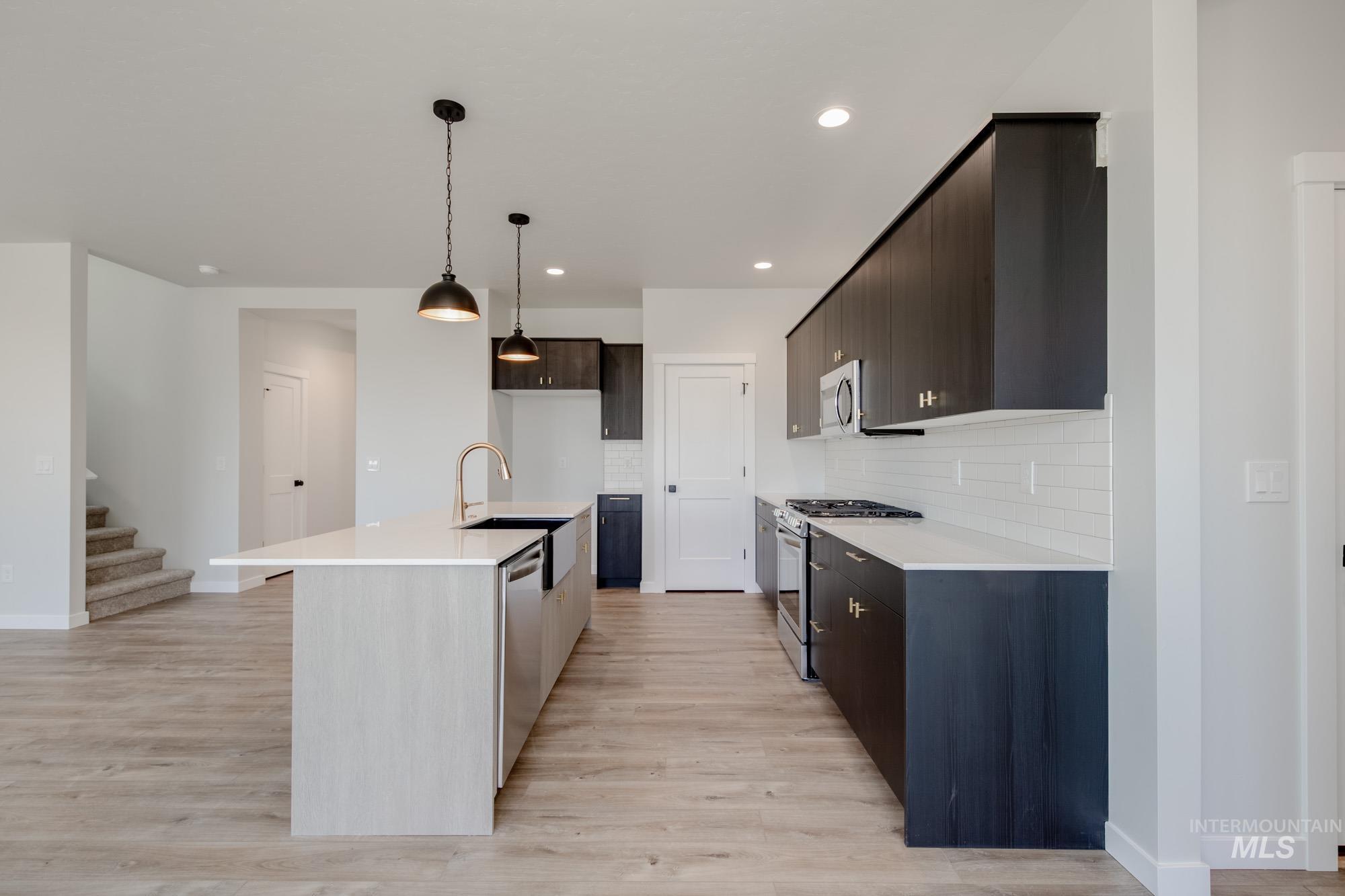 Kitchen with appliances with stainless steel finishes, light wood finished floors, light countertops, and recessed lighting