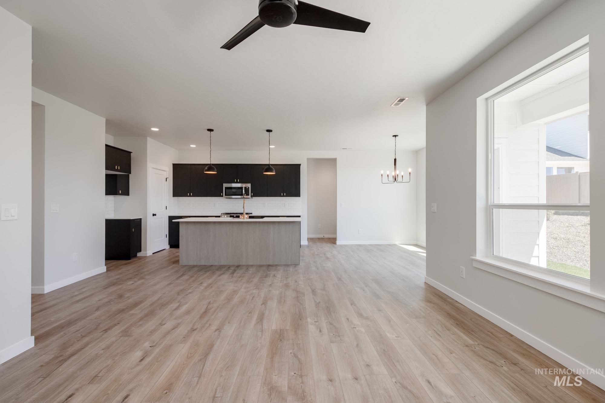 Unfurnished living room with a chandelier, a ceiling fan, light wood-type flooring, and recessed lighting