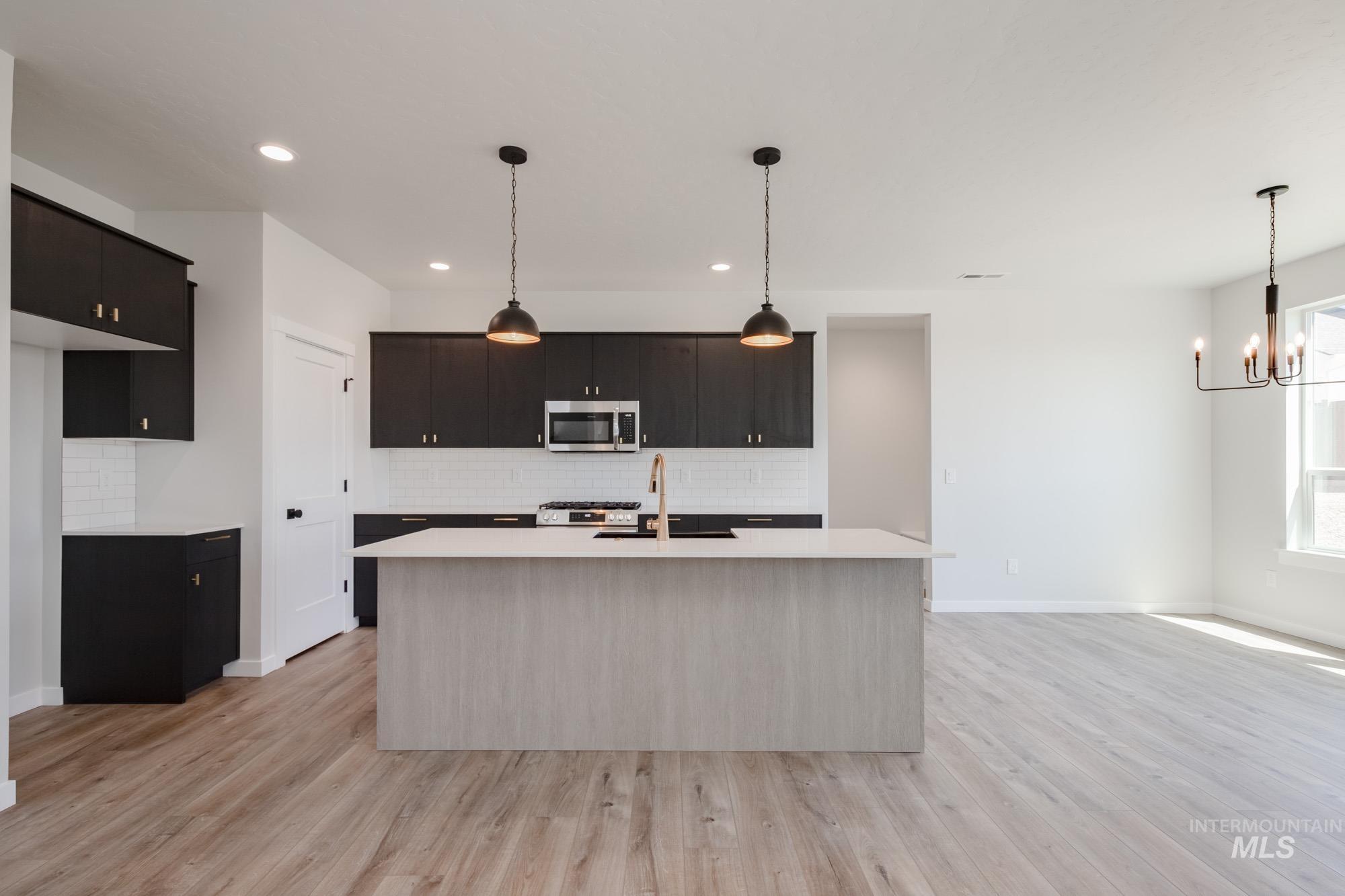 Kitchen featuring stainless steel microwave, light countertops, tasteful backsplash, light wood finished floors, and recessed lighting