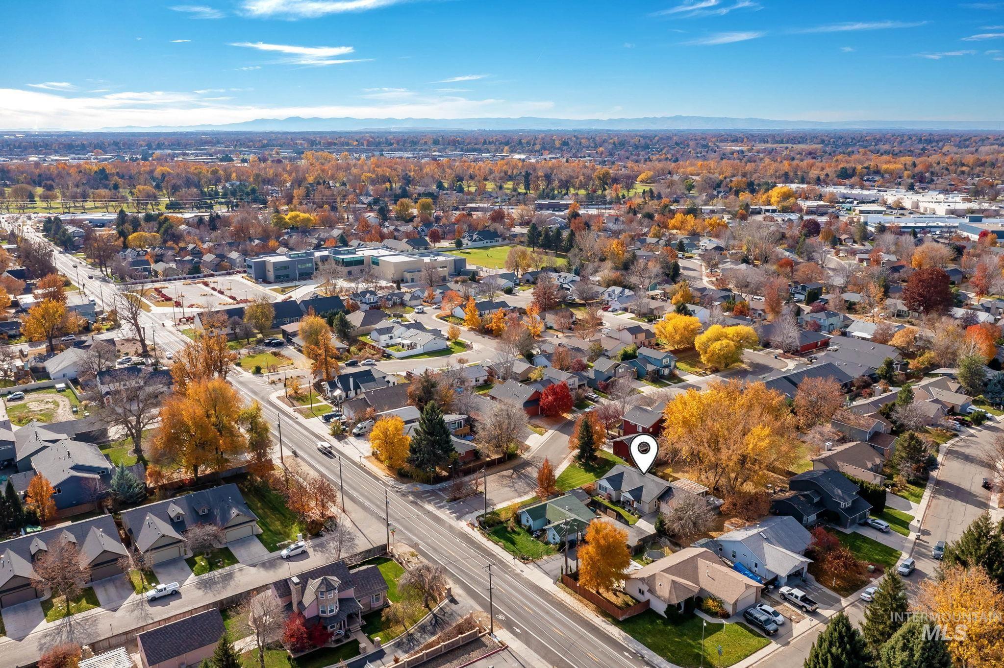 Aerial view of property and surrounding area featuring nearby suburban area and a mountainous background