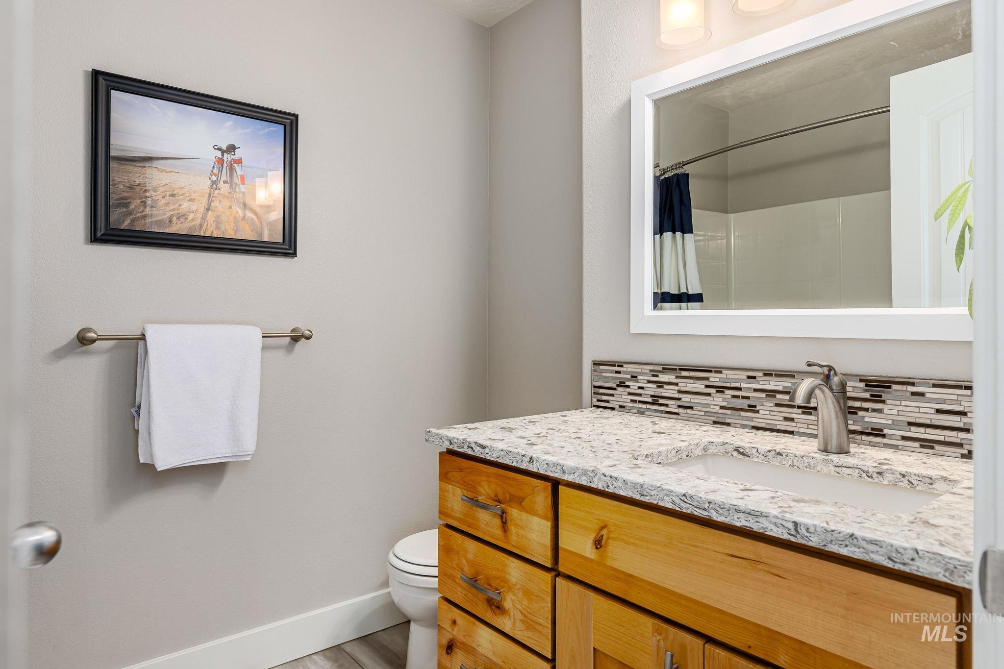Full bathroom featuring vanity, backsplash, and a shower with shower curtain