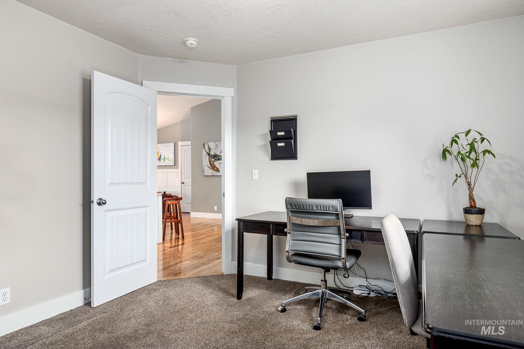 Office area with light colored carpet and a textured ceiling