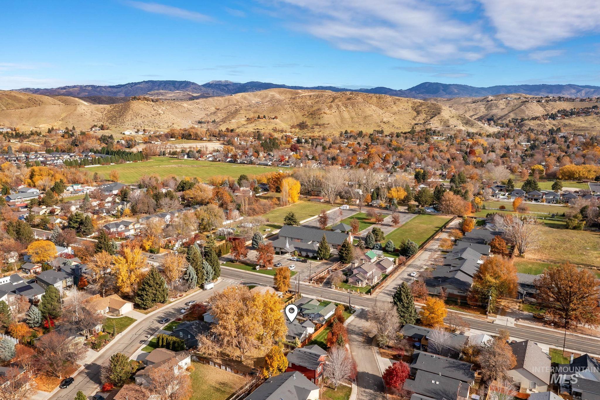 Aerial view of property and surrounding area with a mountainous background and nearby suburban area