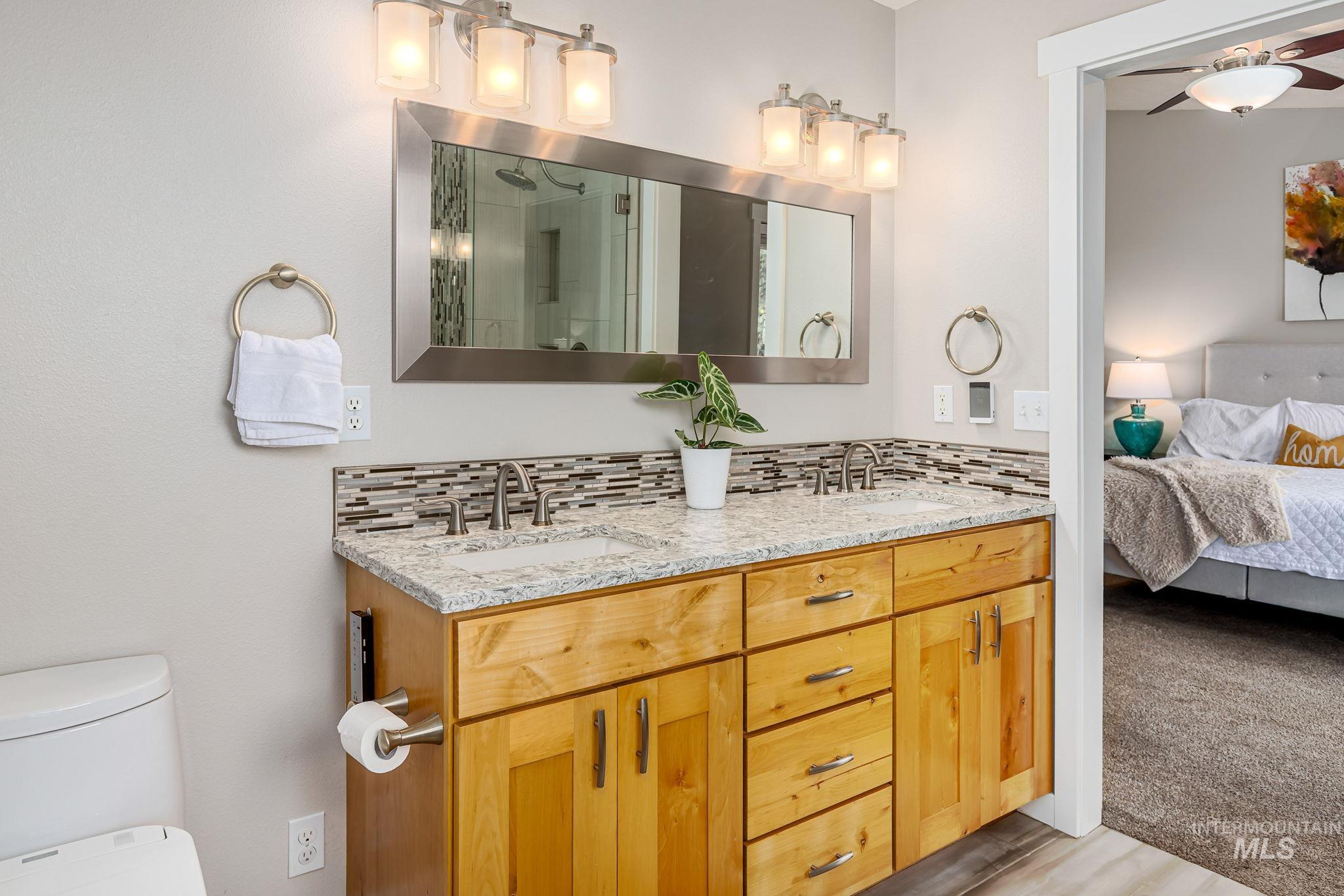 Bathroom featuring double vanity, ensuite bathroom, backsplash, and a shower stall