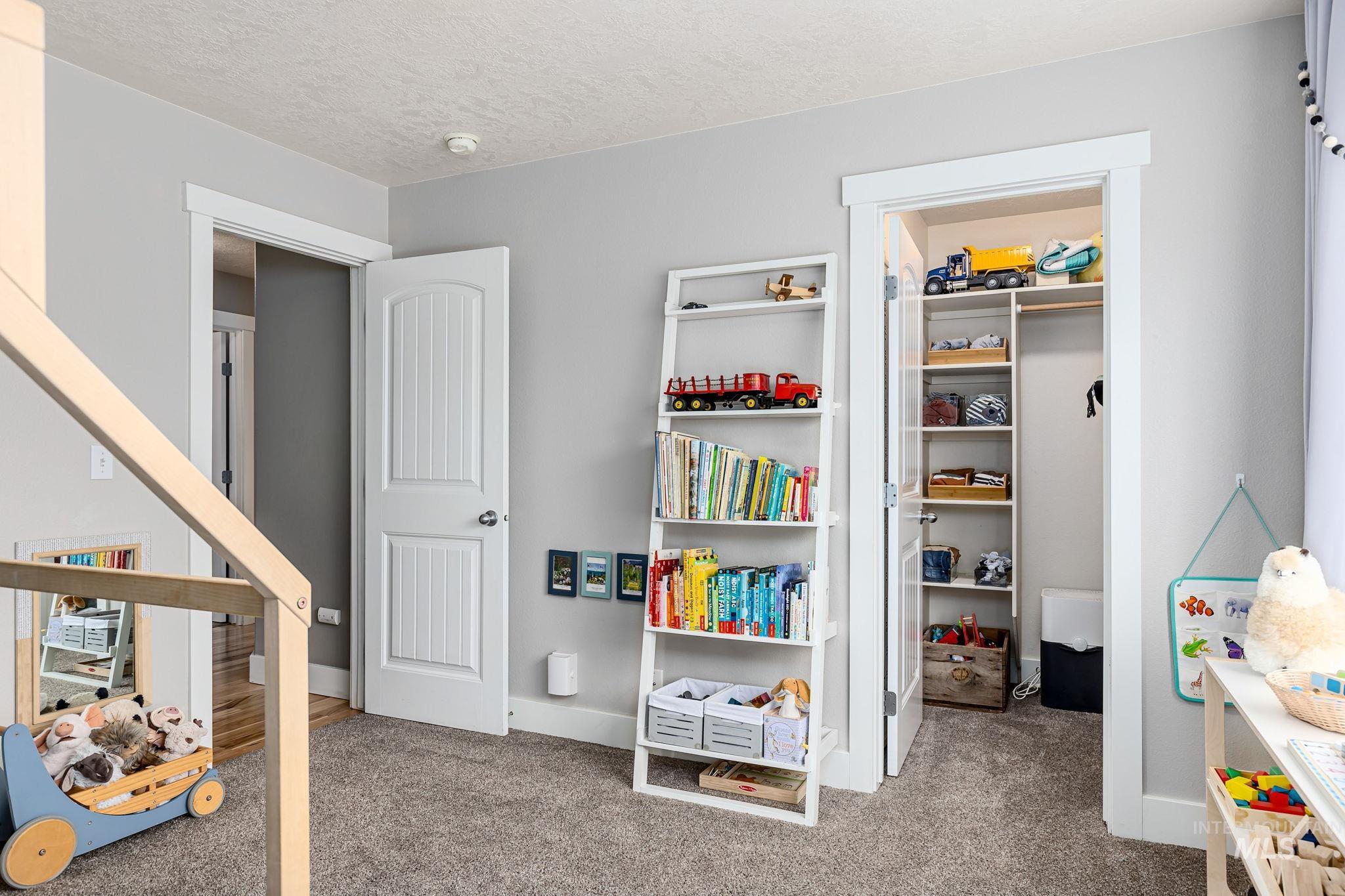 Bedroom with light colored carpet, a textured ceiling, and a walk in closet