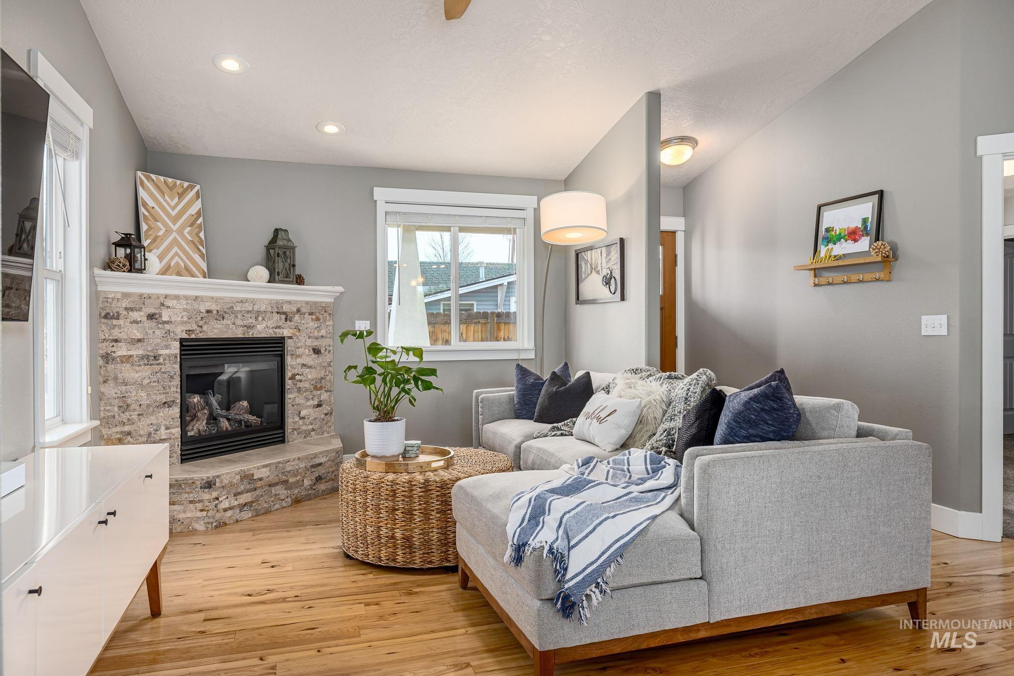 Living area featuring light wood-type flooring, a stone fireplace, and recessed lighting