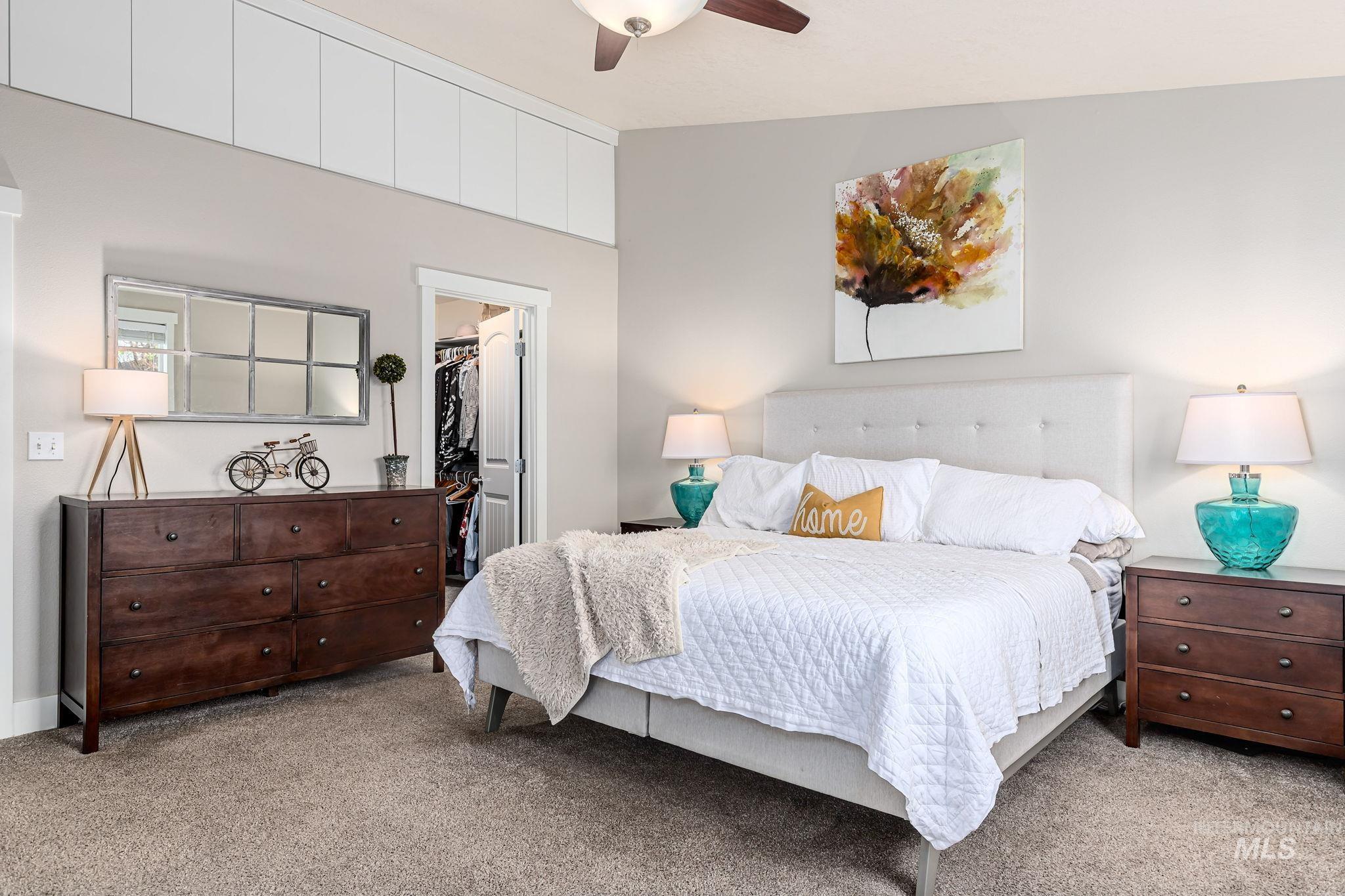Bedroom featuring a walk in closet, light carpet, and a ceiling fan