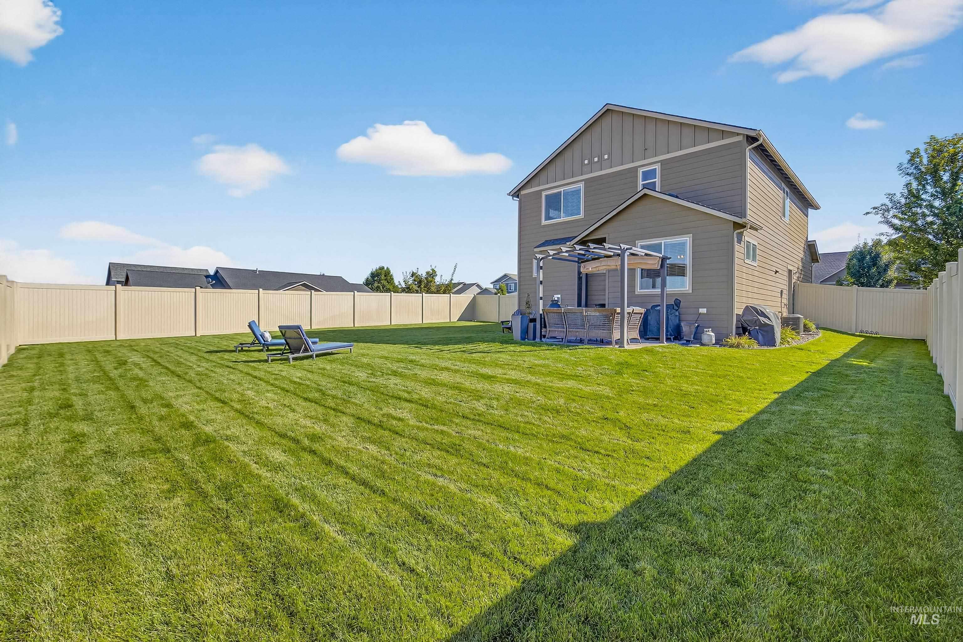 Back of property featuring a fenced backyard, board and batten siding, and a patio area