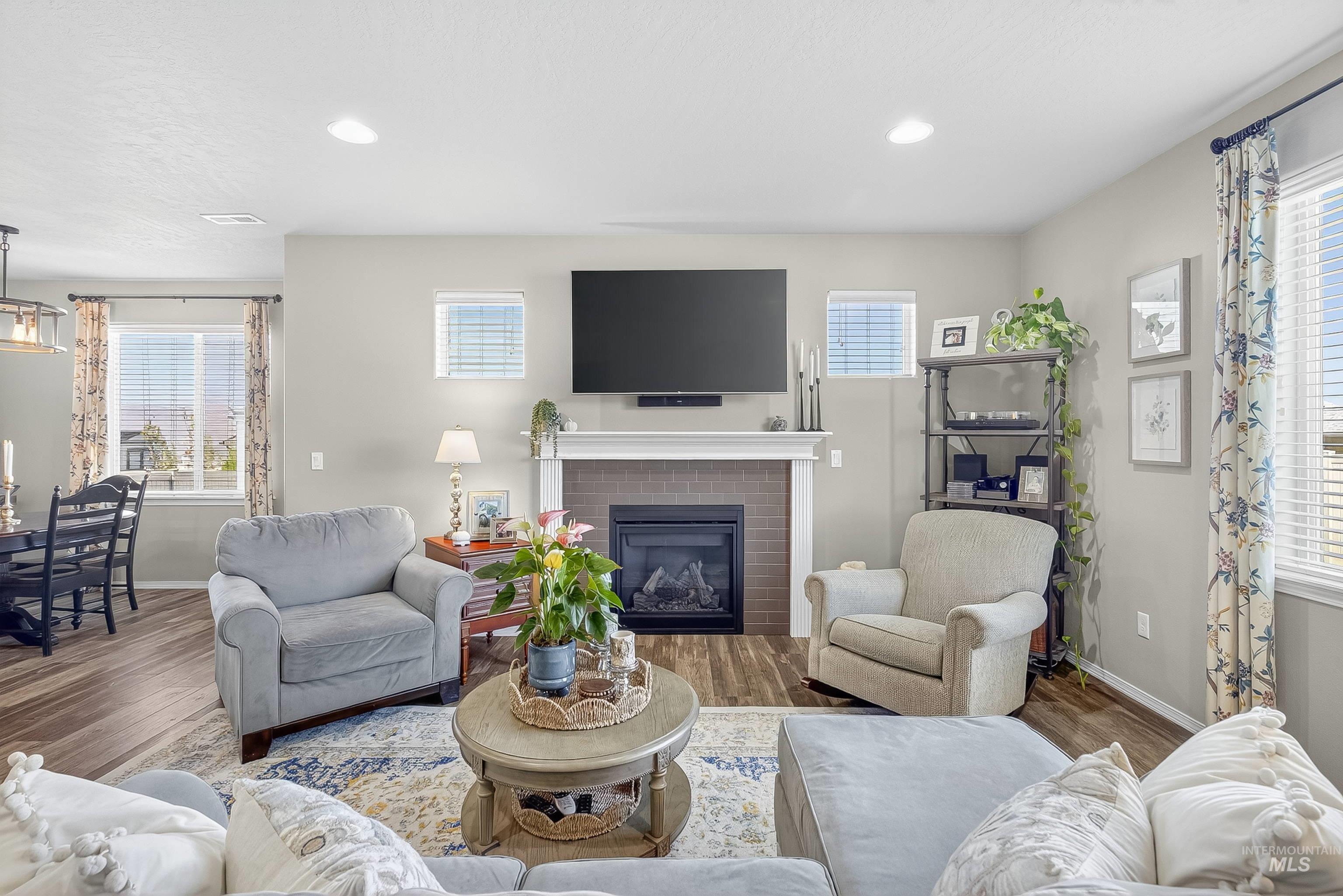 Living room featuring plenty of natural light, a brick fireplace, wood finished floors, and recessed lighting