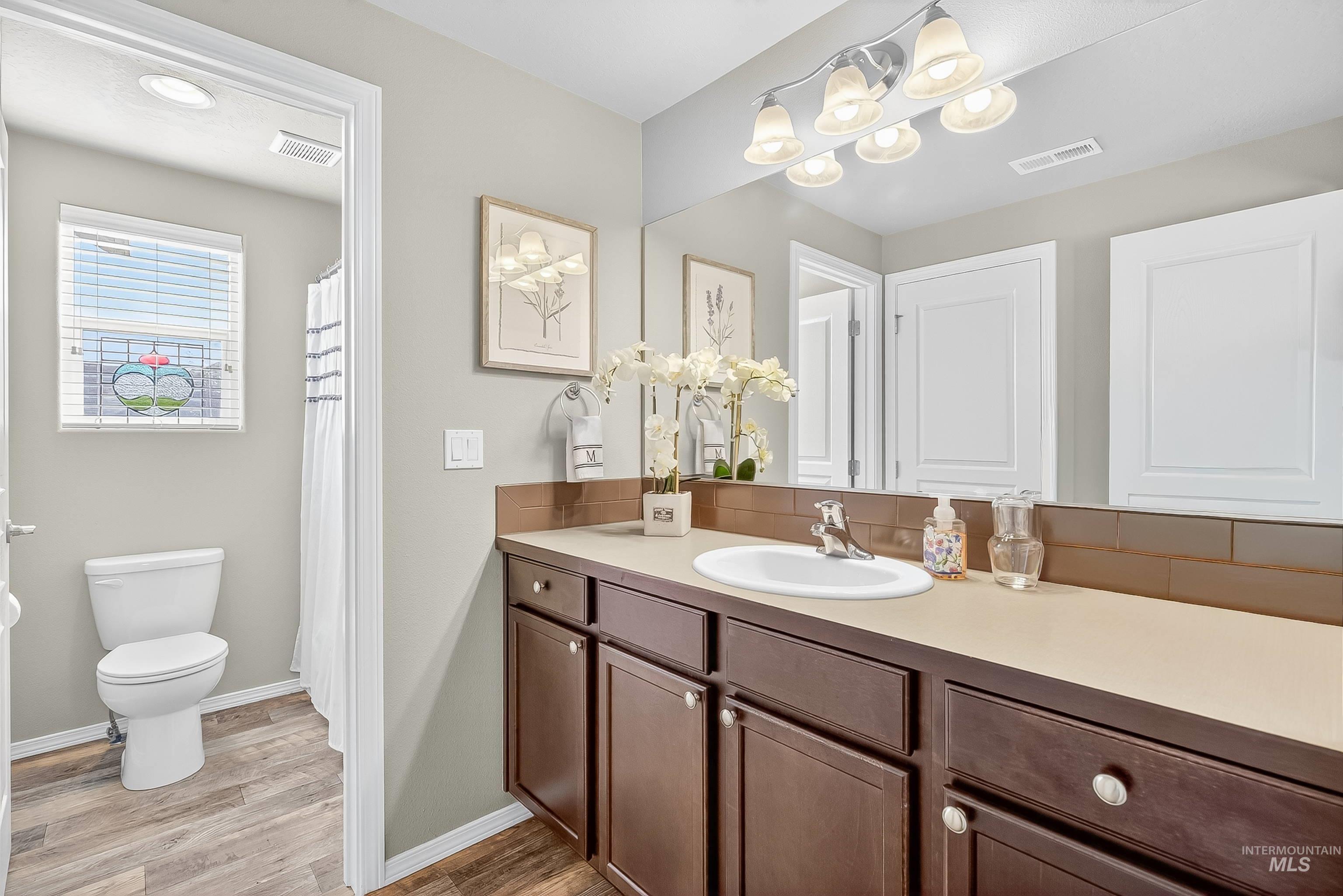 Bathroom with vanity, light wood-style flooring, decorative backsplash, and a shower with shower curtain