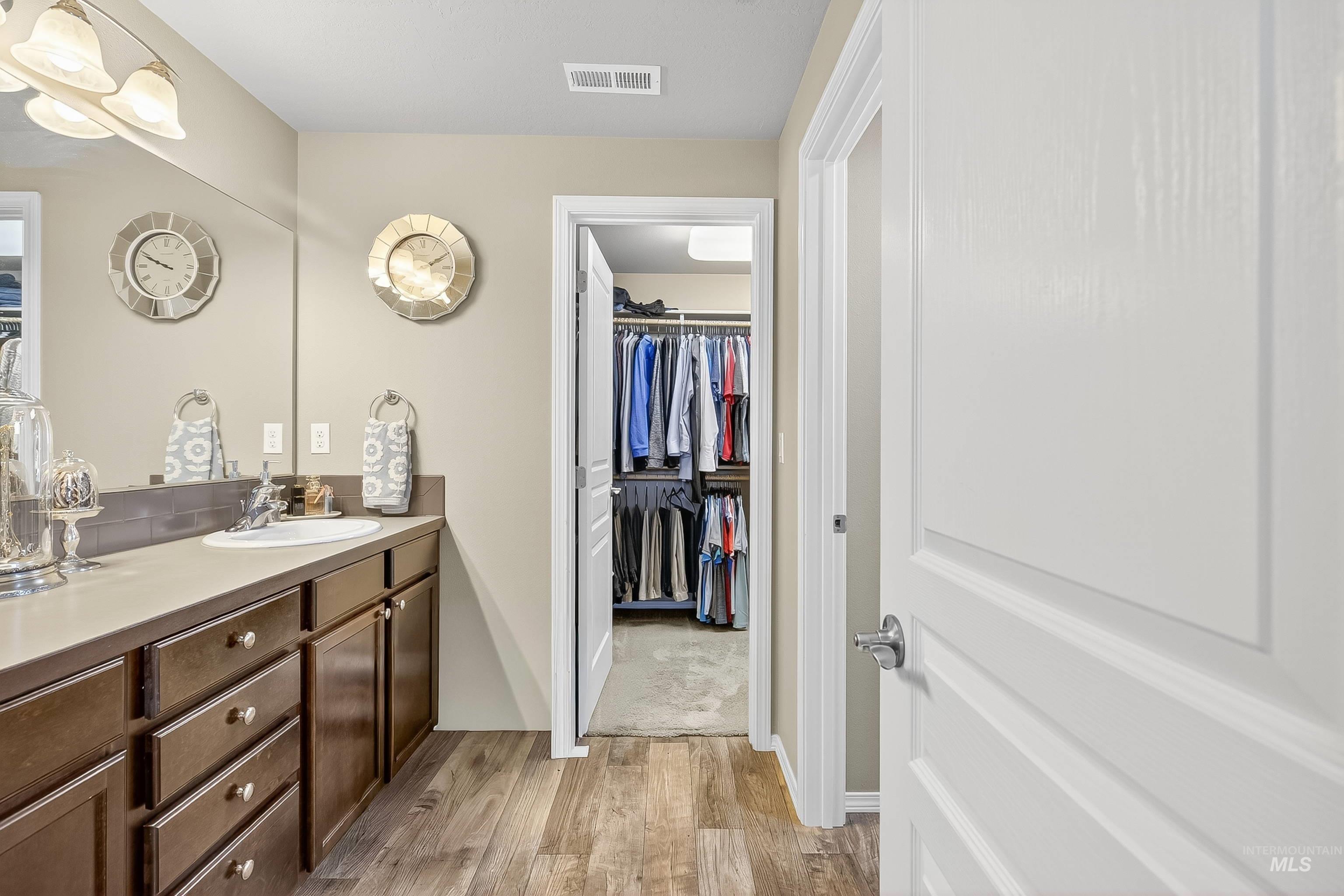 Bathroom featuring light wood-style floors, vanity, and a spacious closet