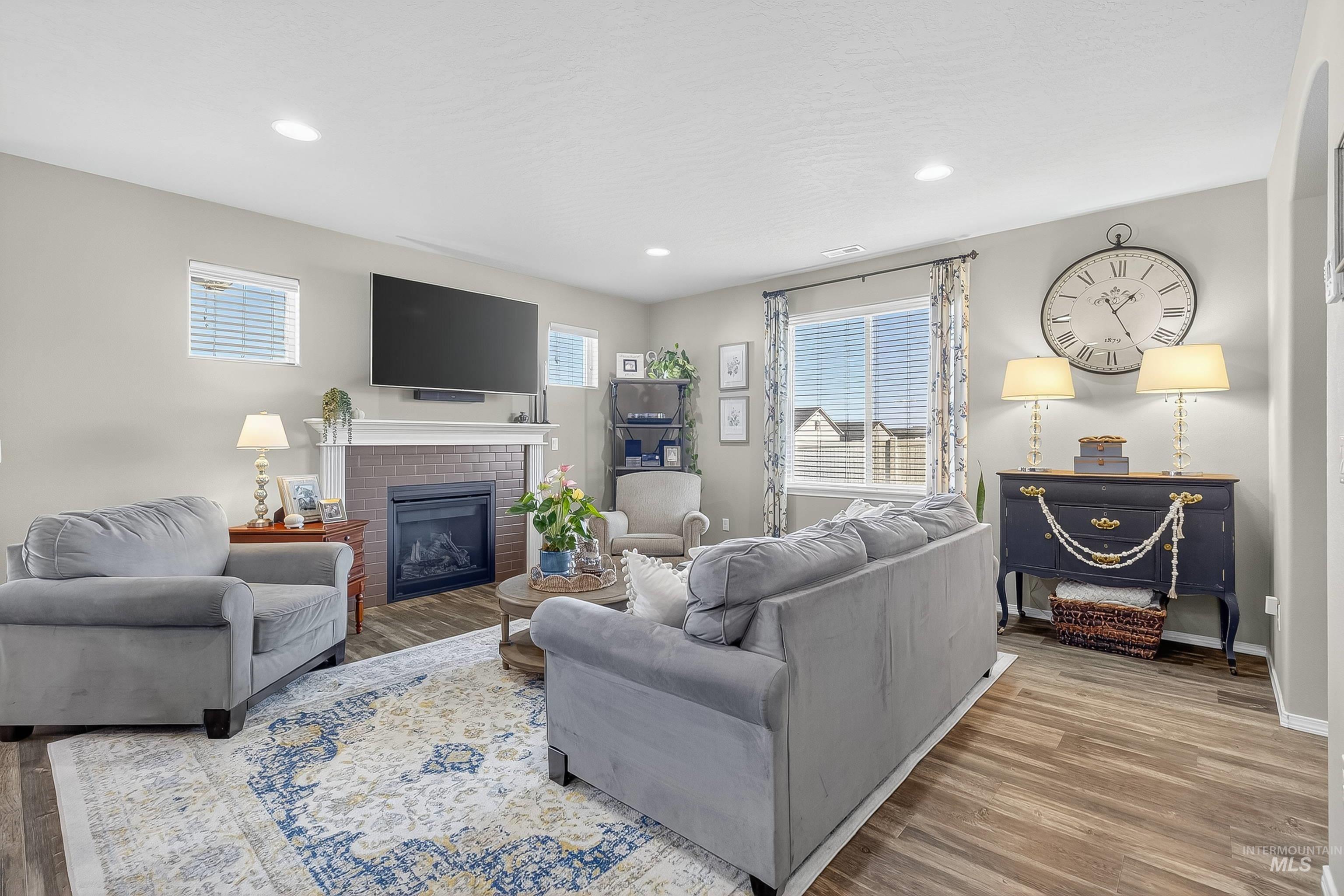 Living room with wood finished floors, a fireplace, and recessed lighting