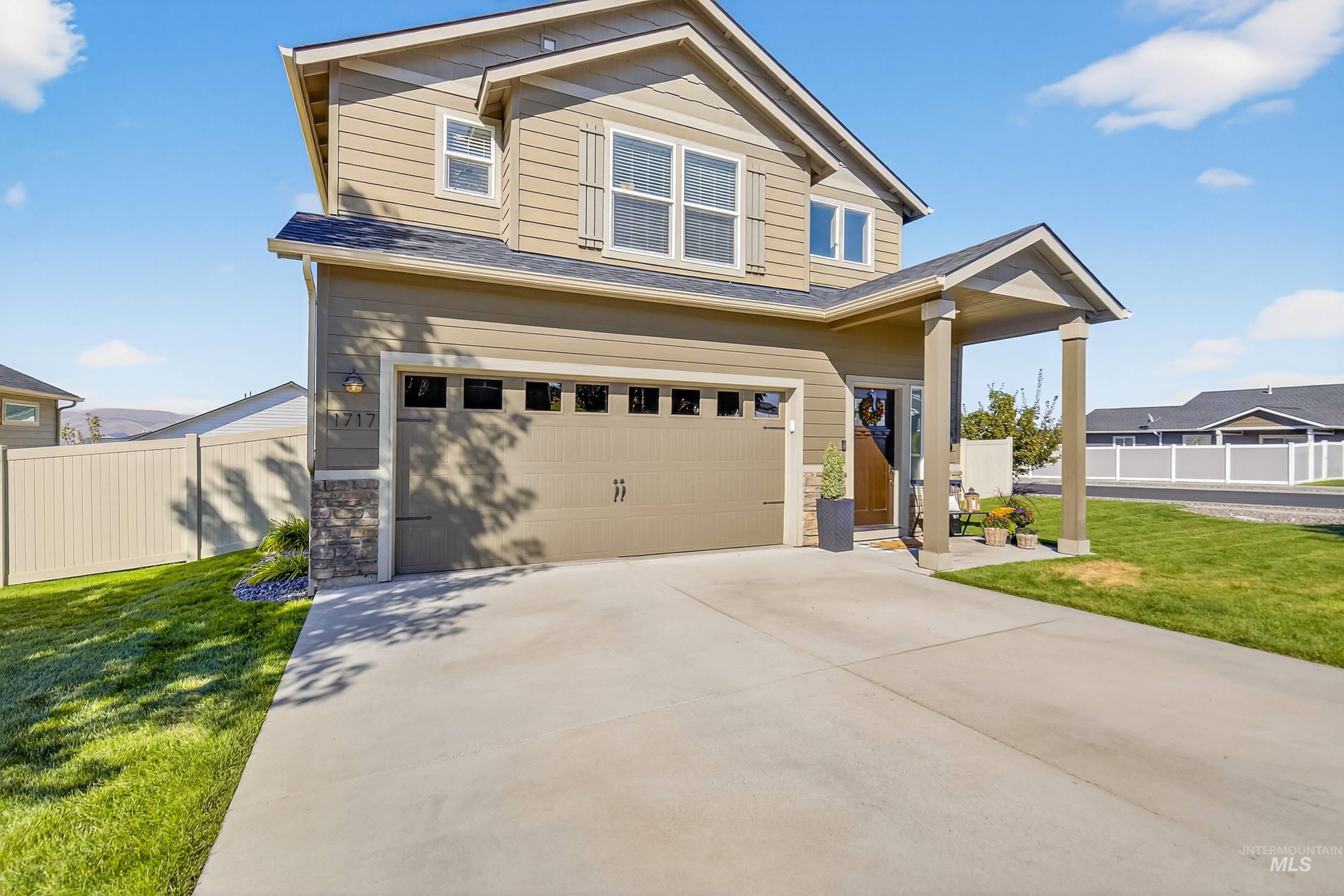 View of front facade with a garage, concrete driveway, stone siding, and roof with shingles