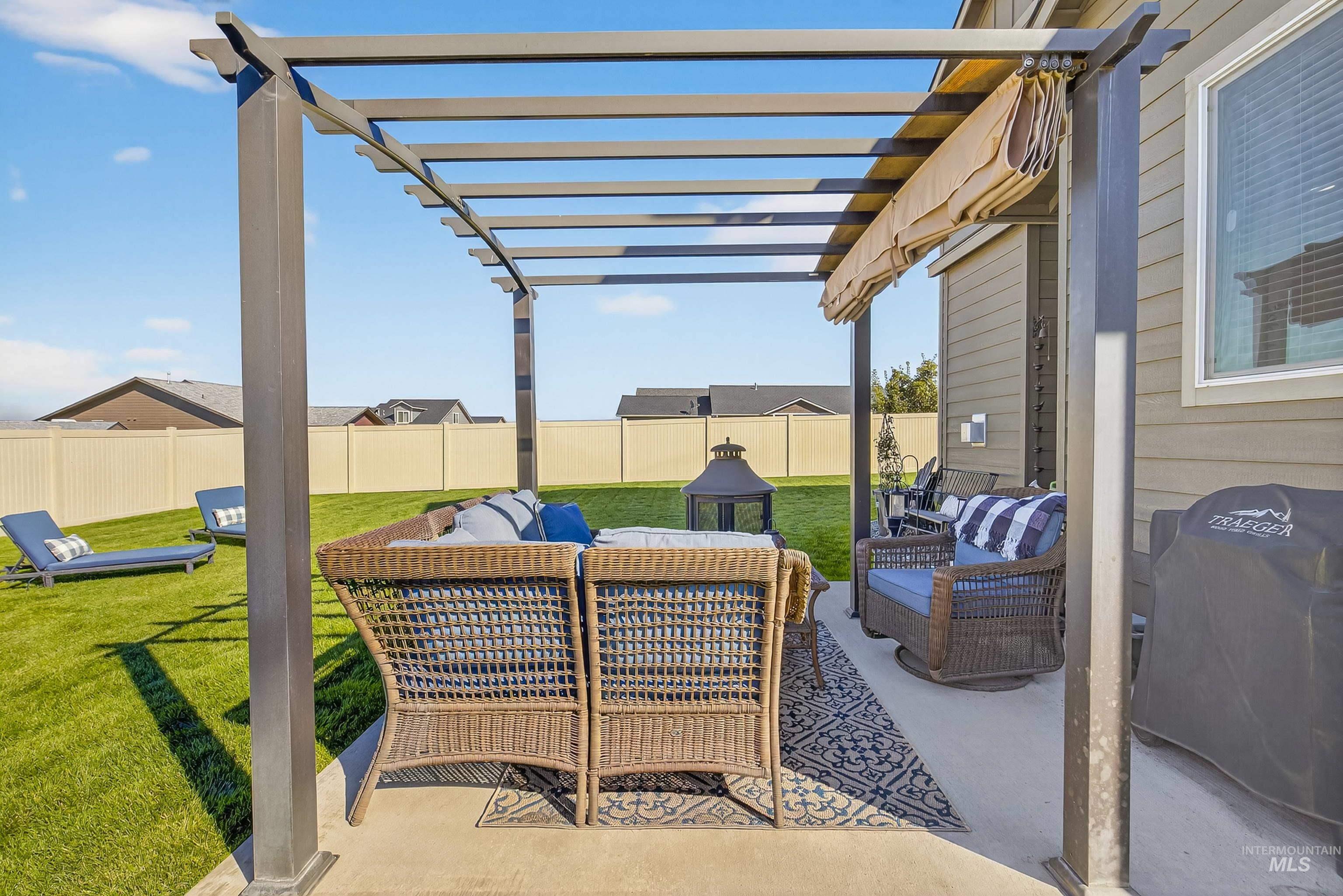 Fenced backyard with a patio area, an outdoor hangout area, grilling area, and a pergola