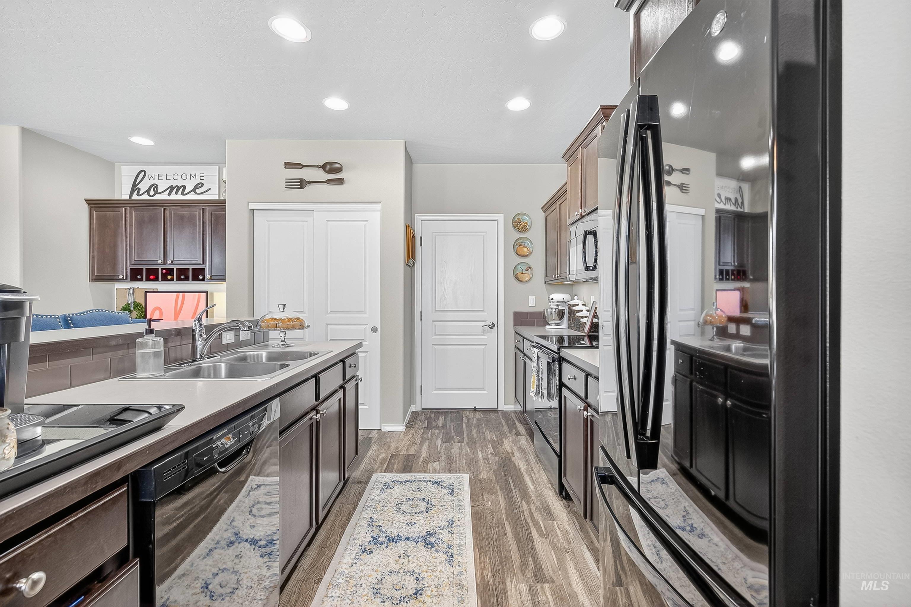 Kitchen featuring black appliances, recessed lighting, light wood-style flooring, dark brown cabinetry, and light countertops