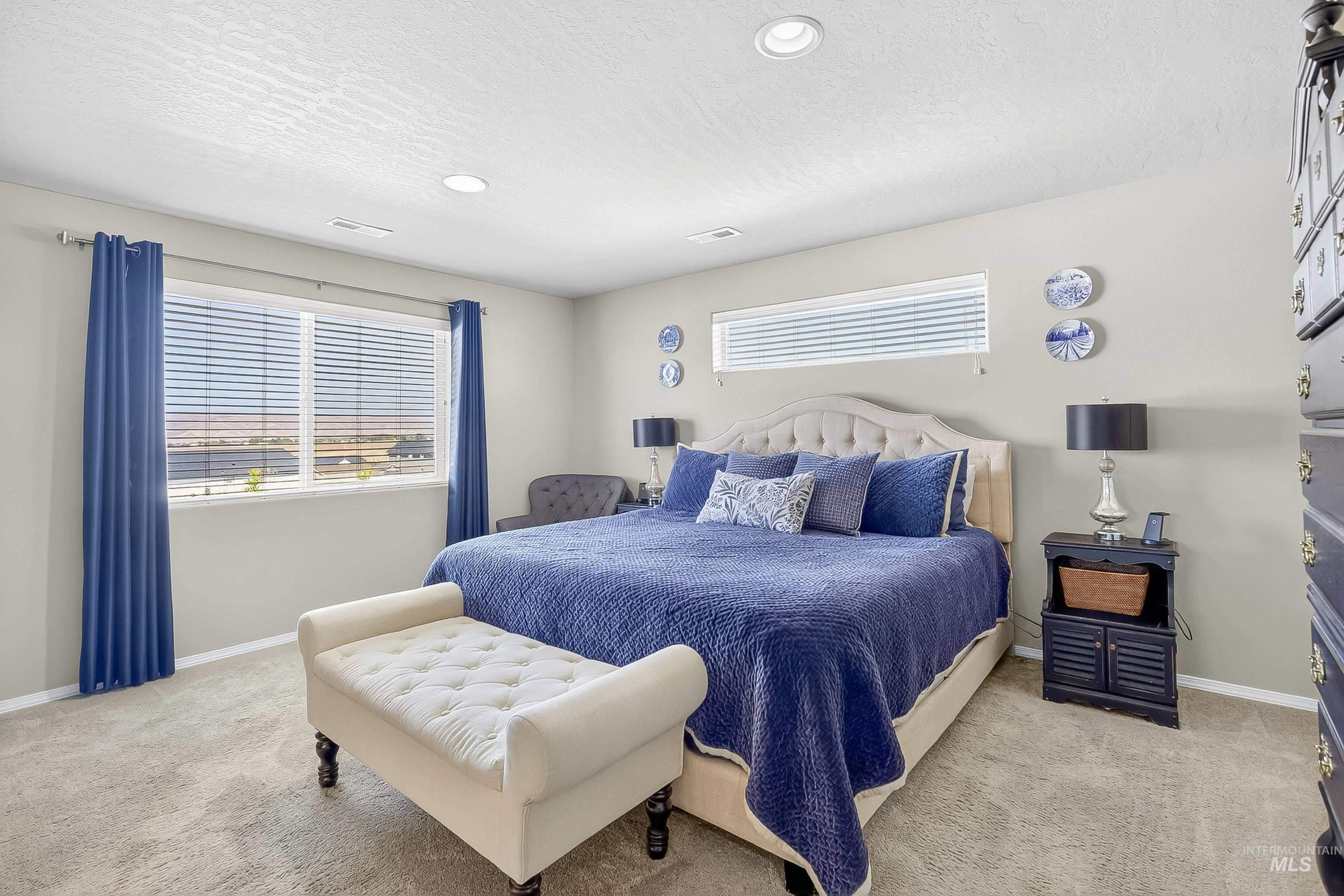Bedroom with a textured ceiling, light carpet, and recessed lighting