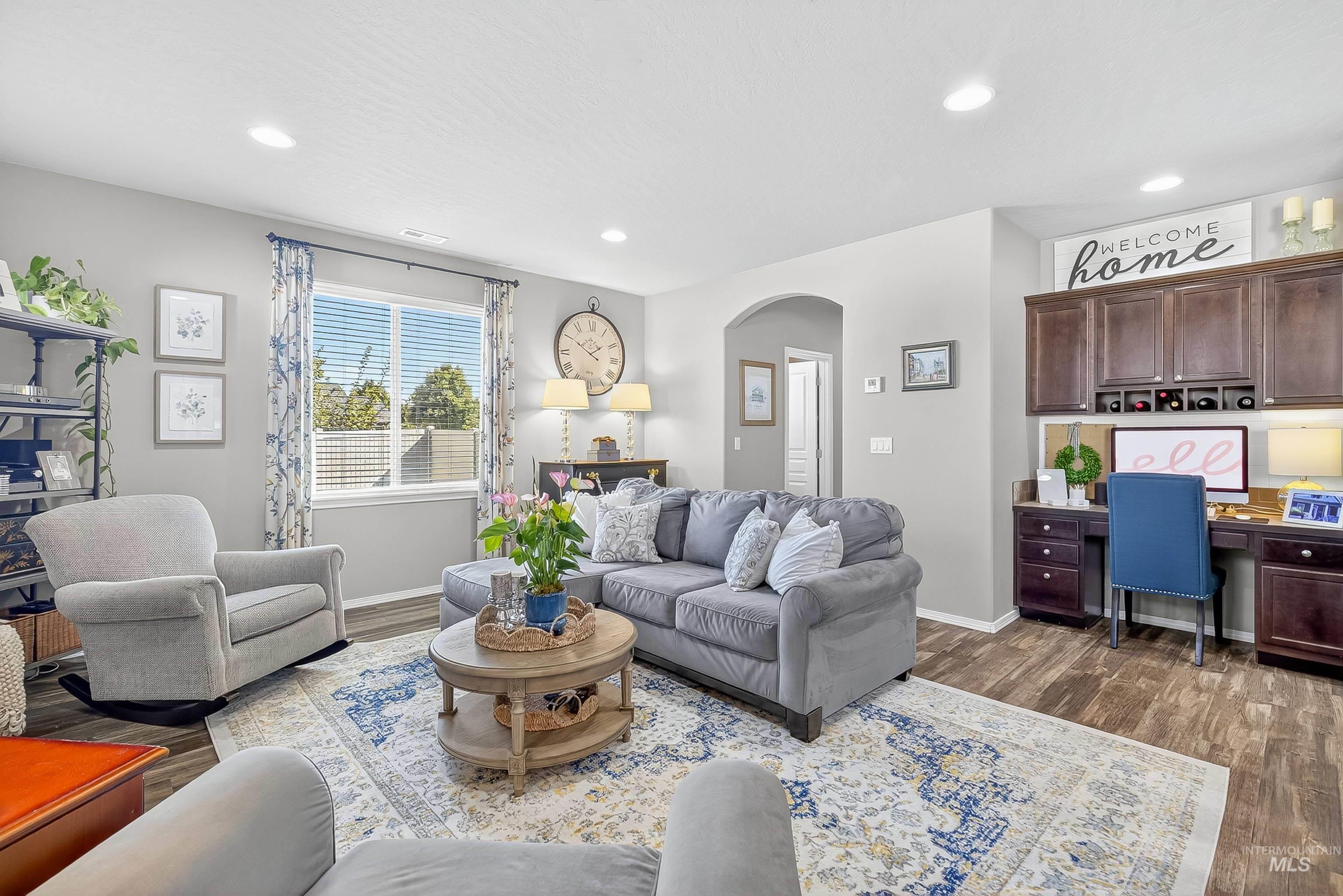 Living room featuring built in desk, arched walkways, dark wood-type flooring, and recessed lighting