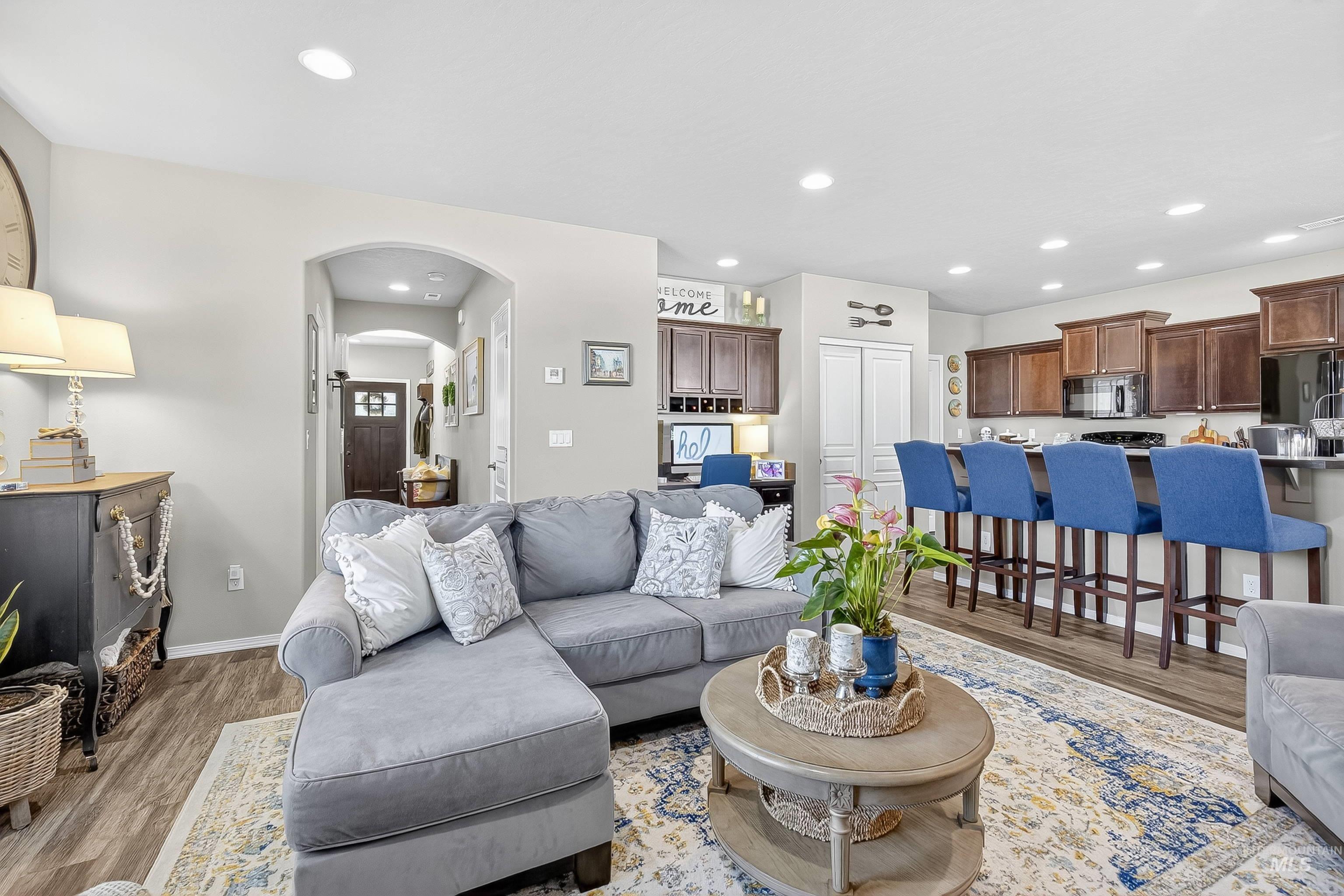 Living area with arched walkways, recessed lighting, and light wood finished floors
