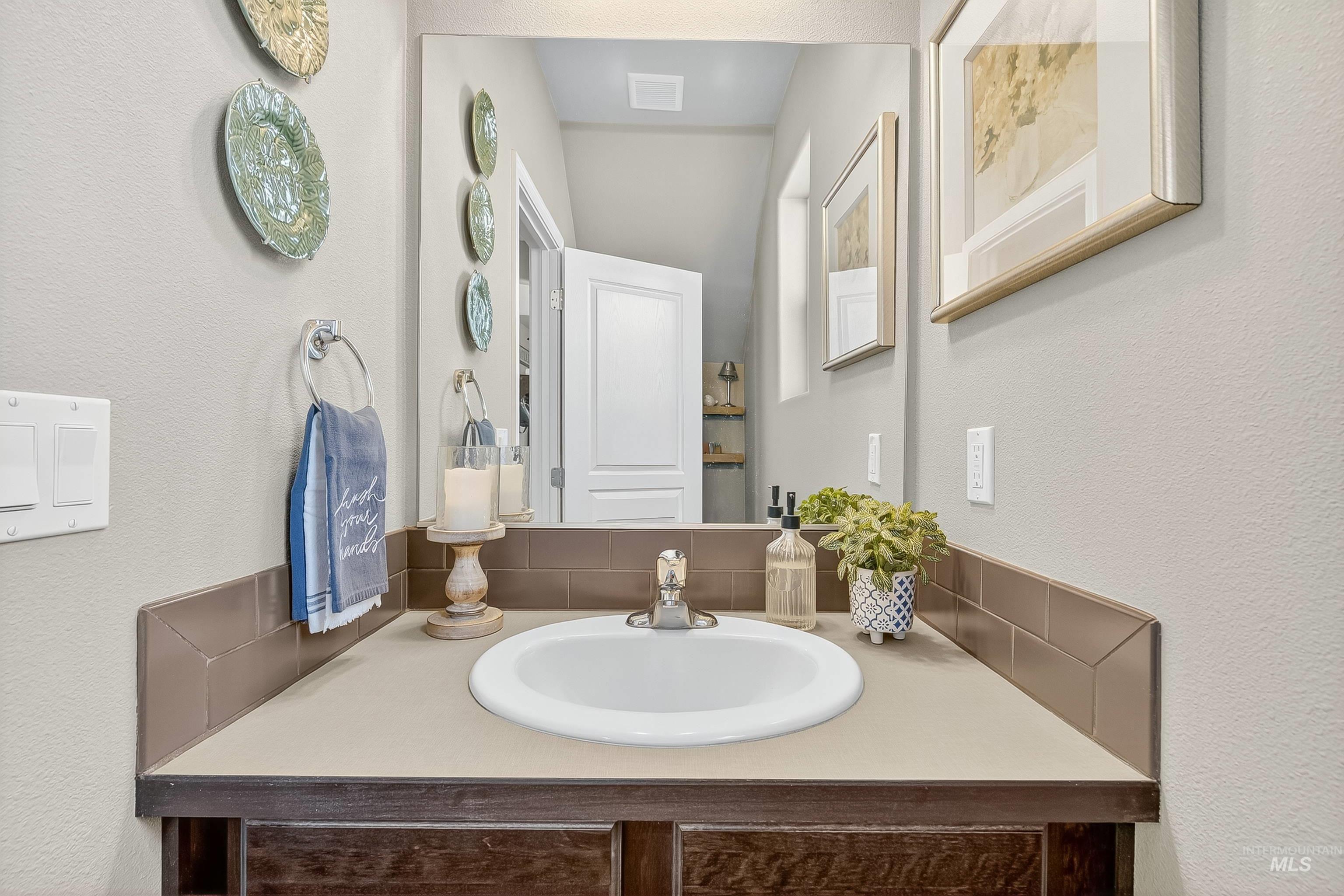 Bathroom featuring a textured wall, vanity, and tasteful backsplash