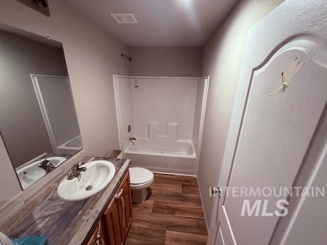 Full bathroom with dark wood-type flooring, tub / shower combination, and vanity