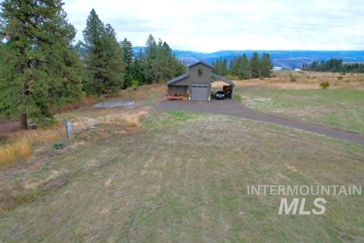 View of yard featuring an outbuilding, a garage, a carport, and driveway