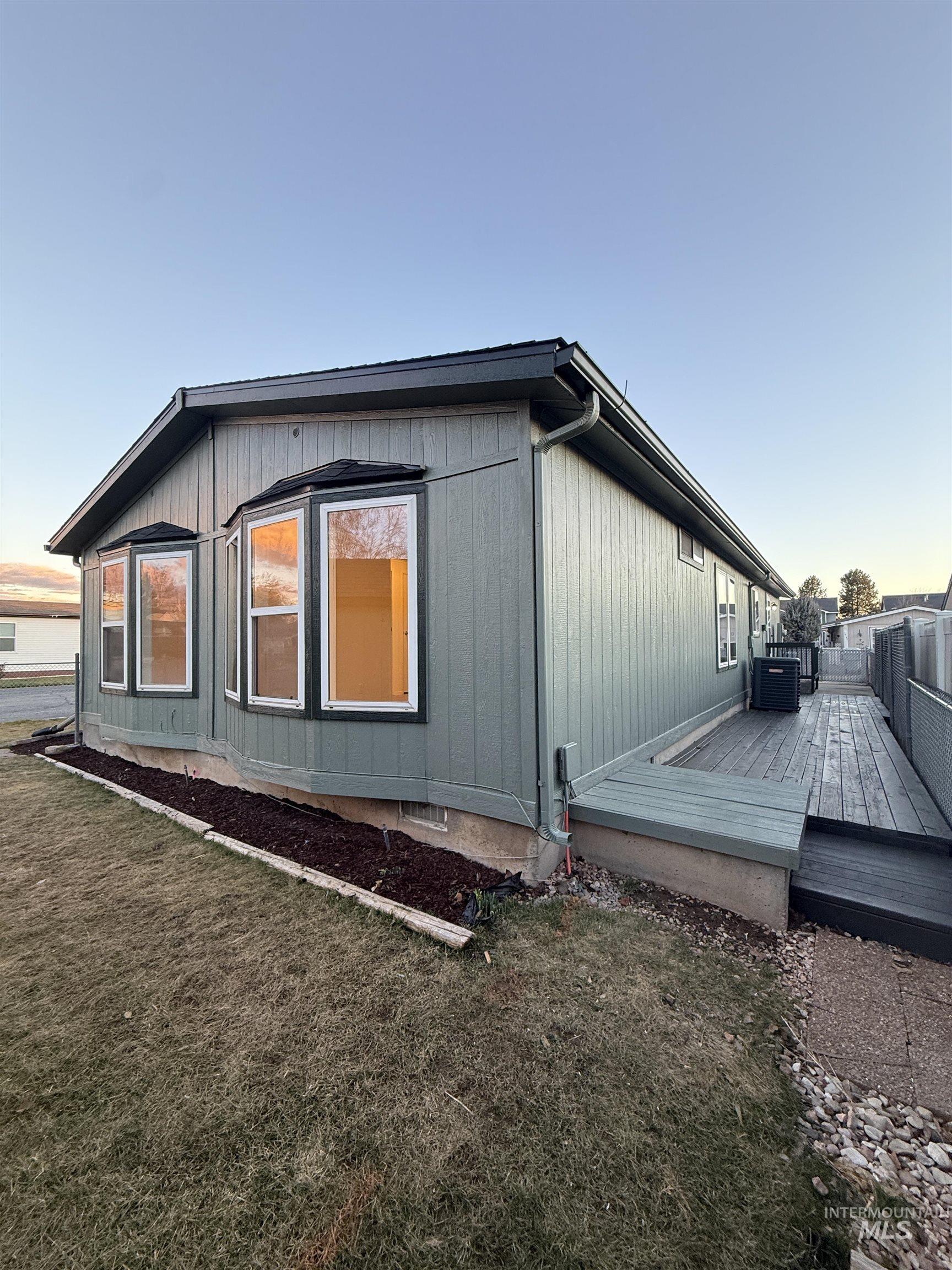 Property exterior at dusk featuring a wooden deck and a yard