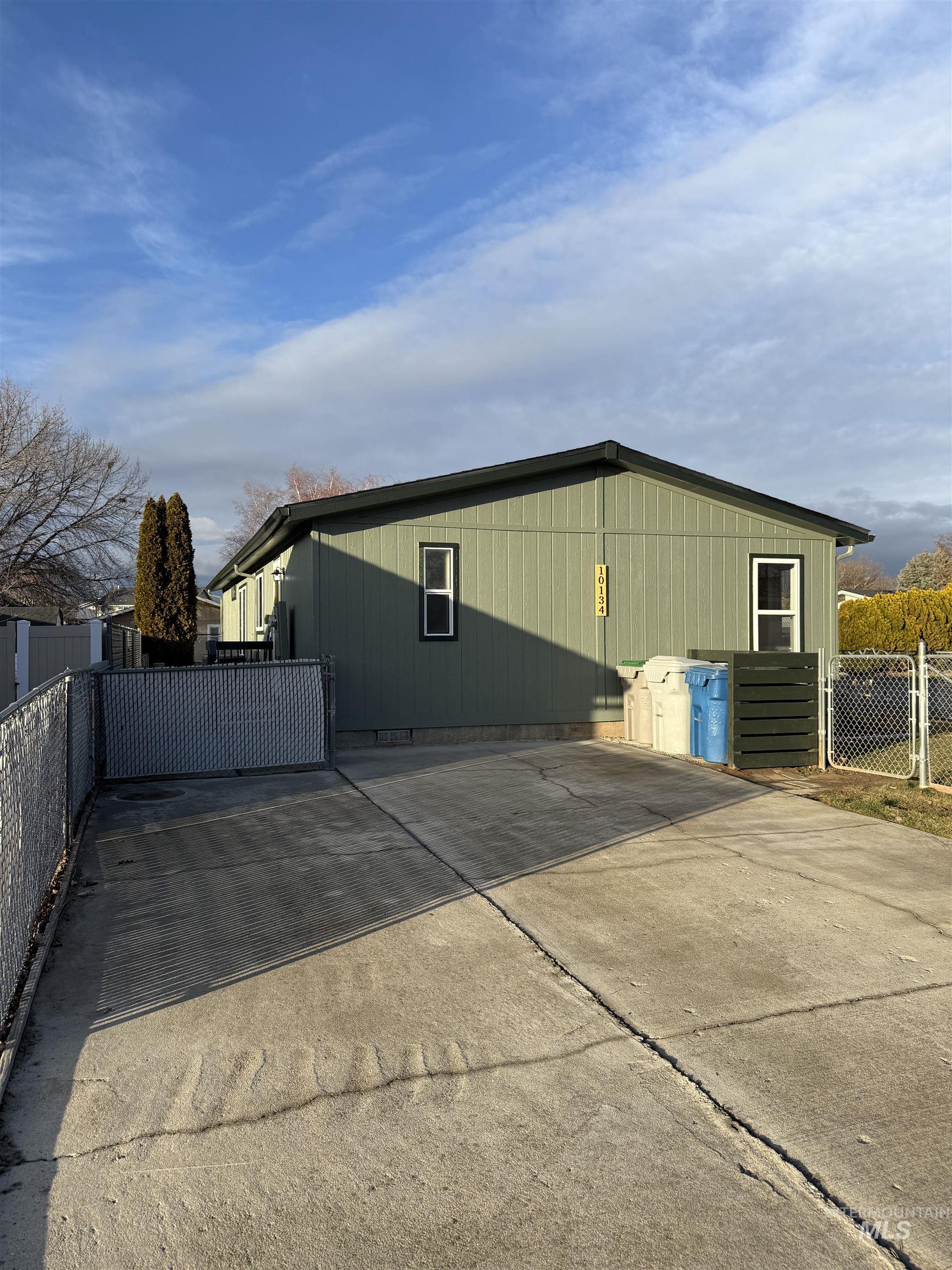 View of property exterior with a gate and concrete driveway
