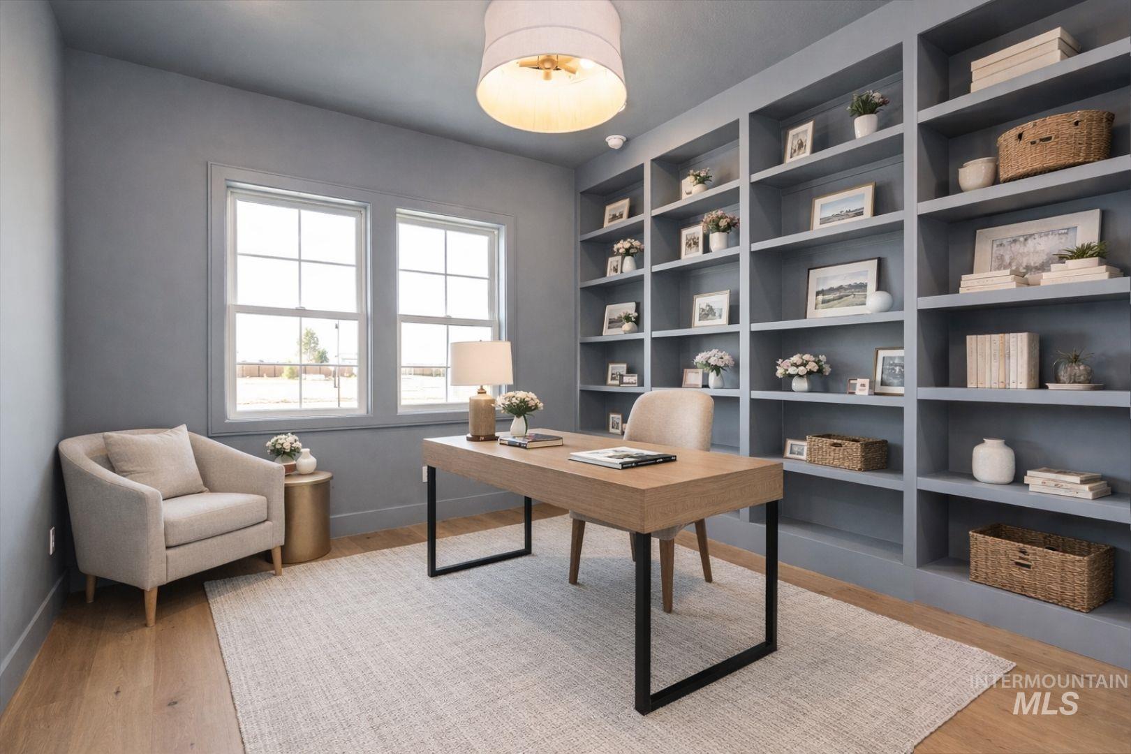 Built-in shelving unit with multiple display tiers, two large double-hung windows, wood-finish flooring, and a flush-mount ceiling light fixture