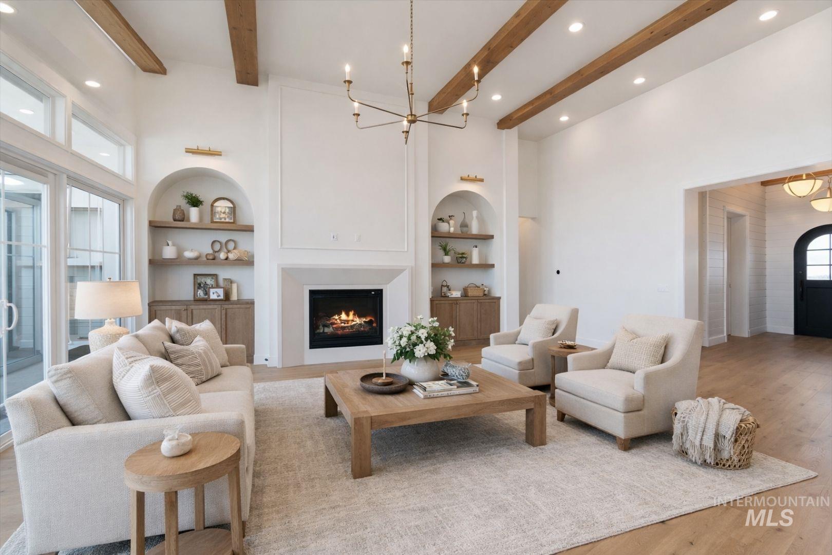 Spacious living area featuring a fireplace with white mantel, exposed ceiling beams, recessed lighting, and wood-finish flooring