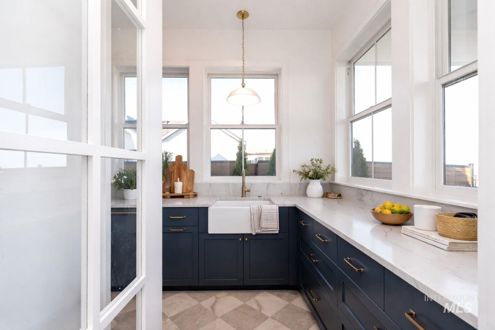 U-shaped kitchen with dark blue cabinetry, brass hardware, and light-toned countertops