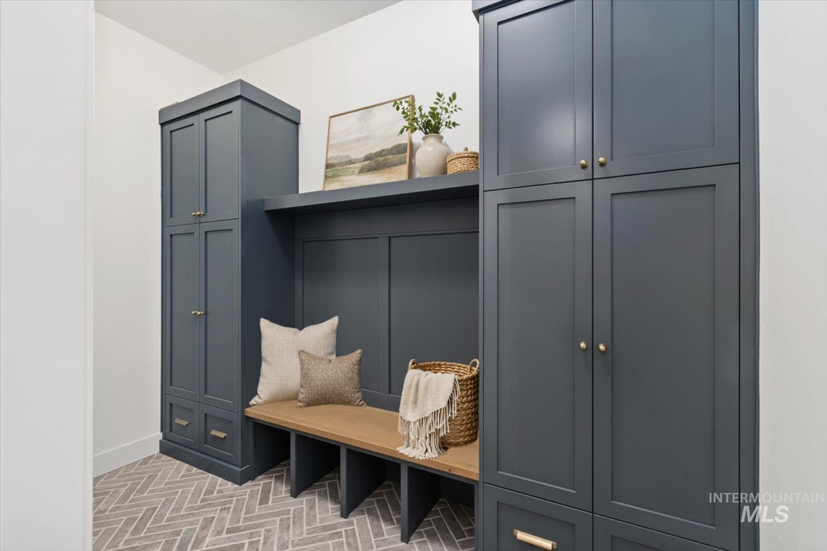 Built-in storage solutions featuring shaker-style cabinetry, a wood-finish bench, and herringbone pattern floor tile