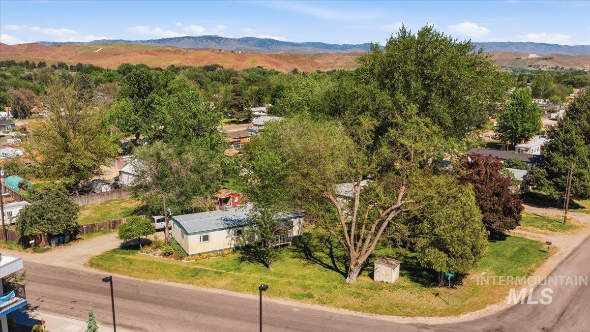Expansive corner lot featuring mature trees and a single-story residence with light-colored siding and a metal roof