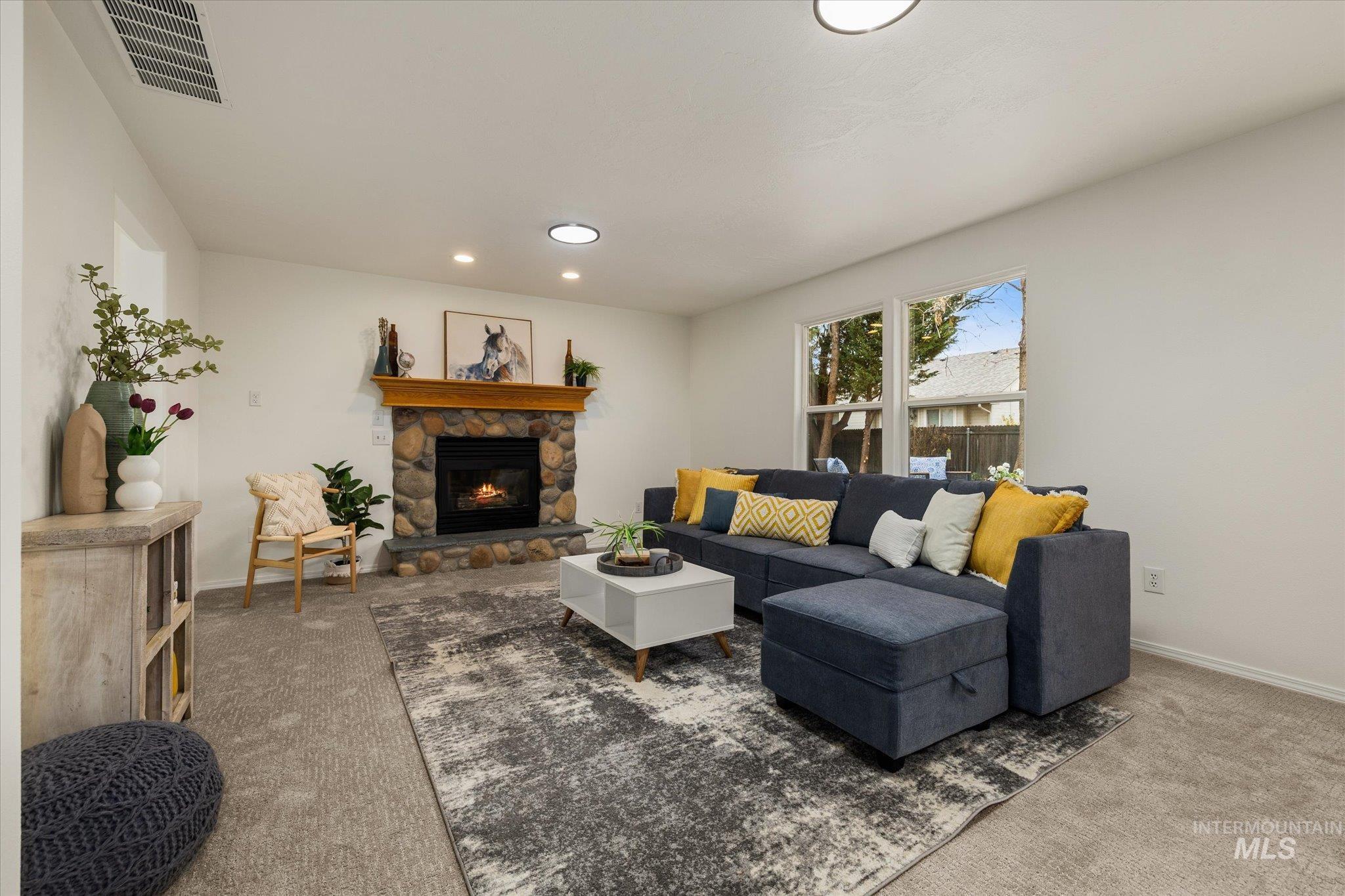 Carpeted living room with recessed lighting and a stone fireplace