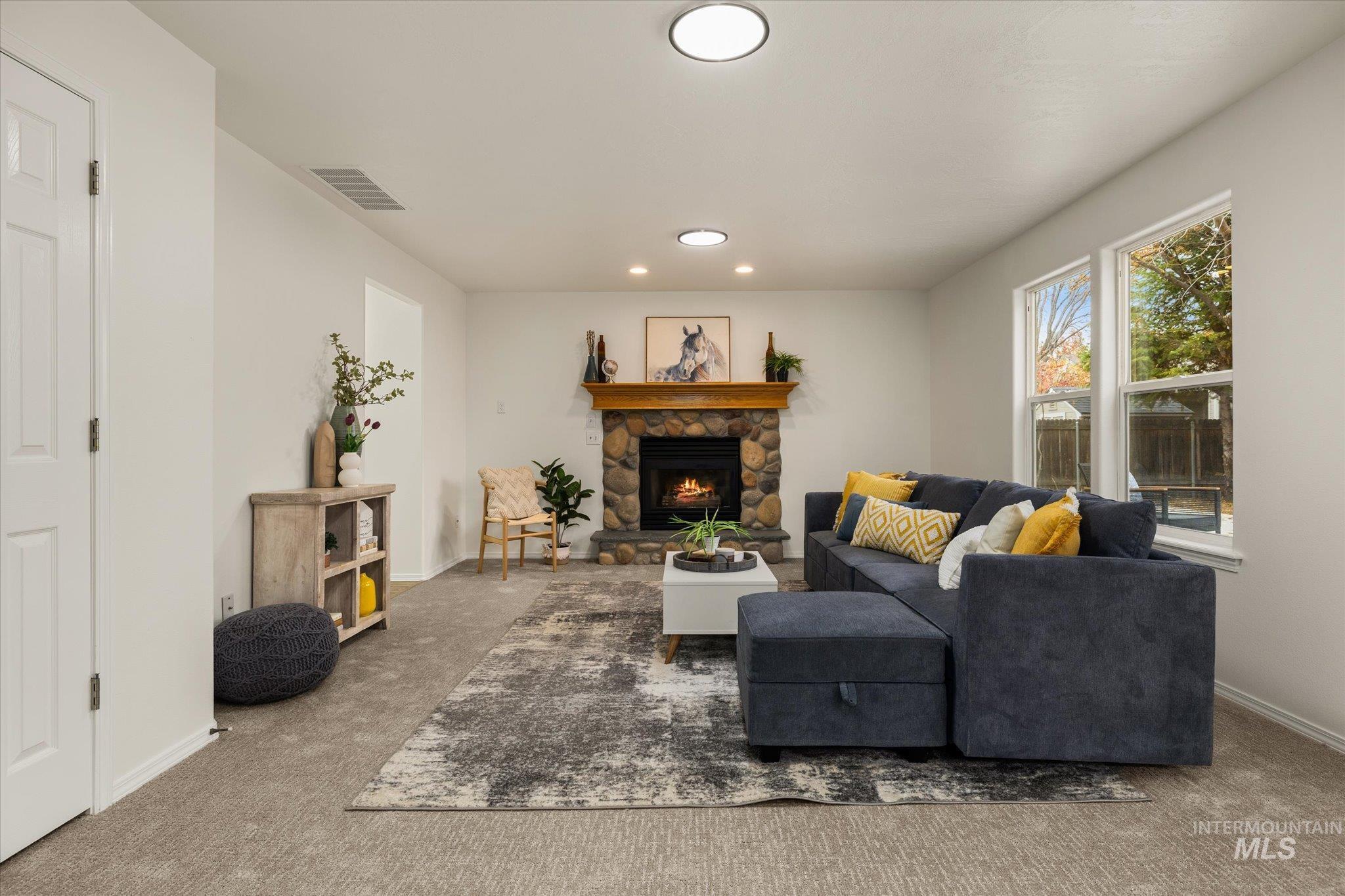 Carpeted living area with recessed lighting and a stone fireplace